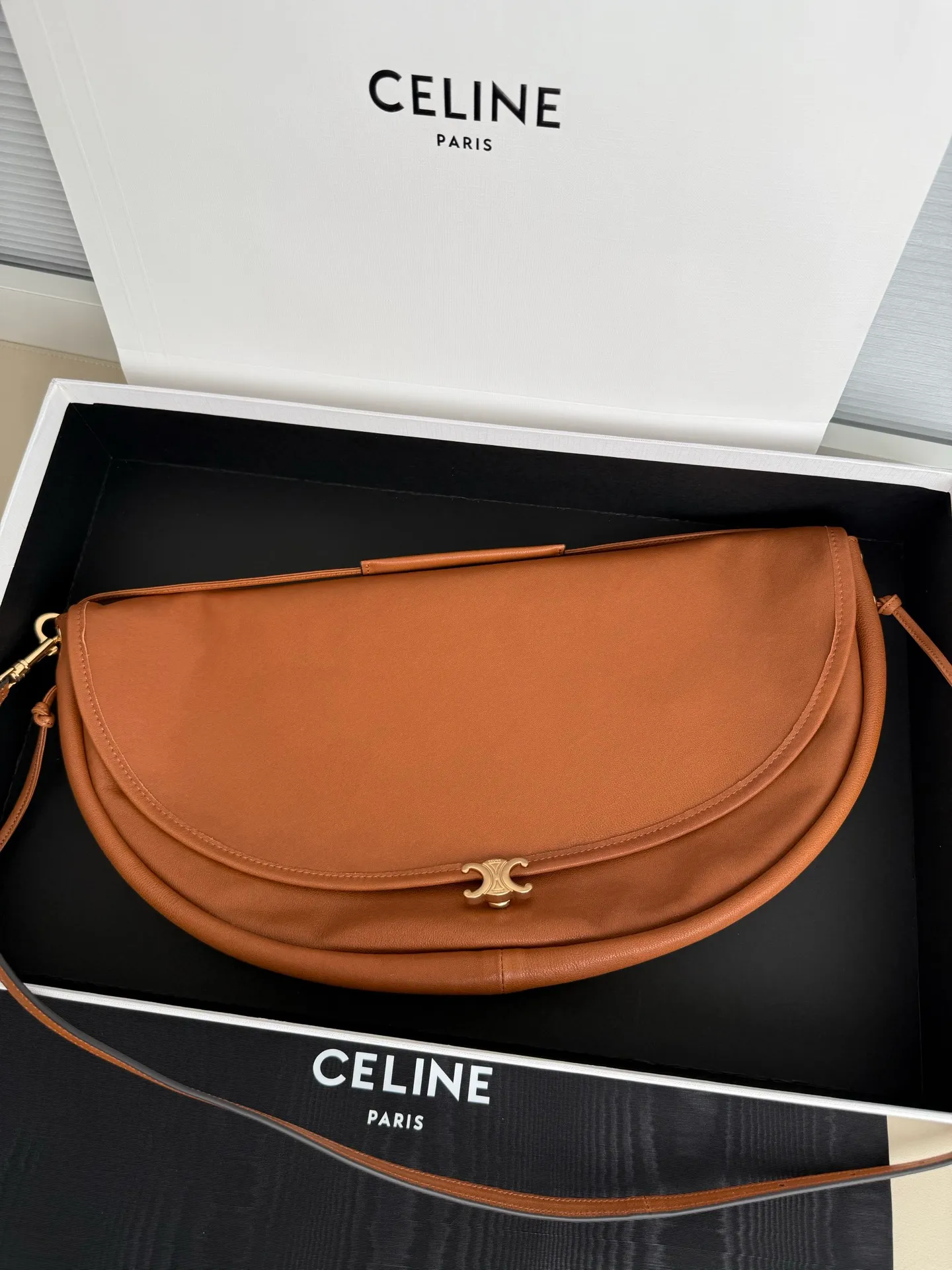 900. Soft Triomphe Halfmoon bag is fashionable✨ CELINE 26SPRING half-moon bag~ Fashionable and special-shaped bag. Large capacity can be used under armpit & one shoulder [kiss an R] I like the shiny leather. The material is shiny lambskin. It is quite light and has a minimalist and neat silhouette. It is fashionable in autumn and winter and can be pinched by the handle✨ Size: 46×19×10 Model: 124142
