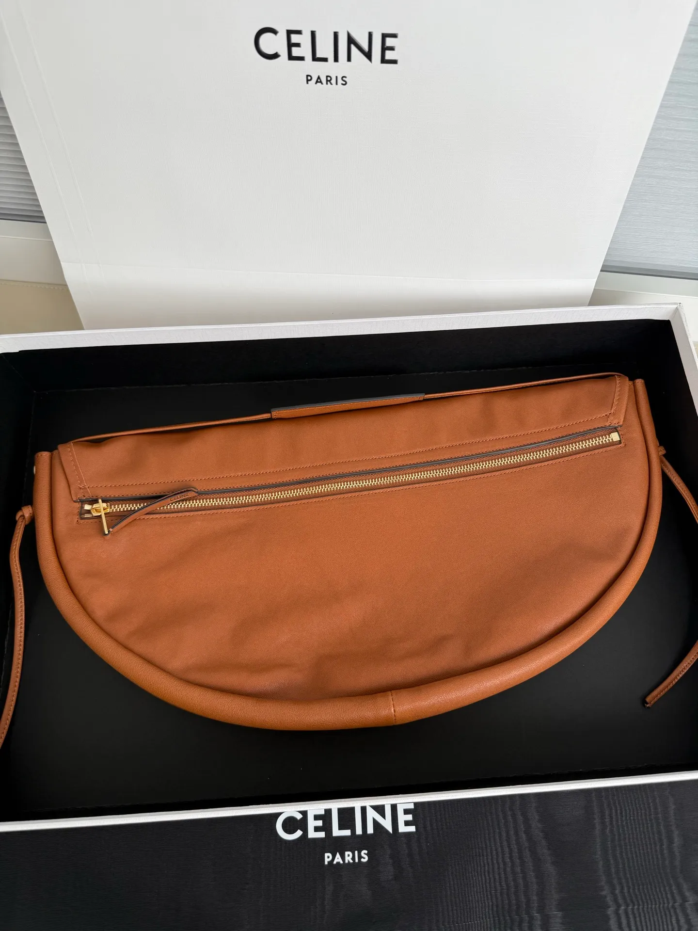 900. Soft Triomphe Halfmoon bag is fashionable✨ CELINE 26SPRING half-moon bag~ Fashionable and special-shaped bag. Large capacity can be used under armpit & one shoulder [kiss an R] I like the shiny leather. The material is shiny lambskin. It is quite light and has a minimalist and neat silhouette. It is fashionable in autumn and winter and can be pinched by the handle✨ Size: 46×19×10 Model: 124142