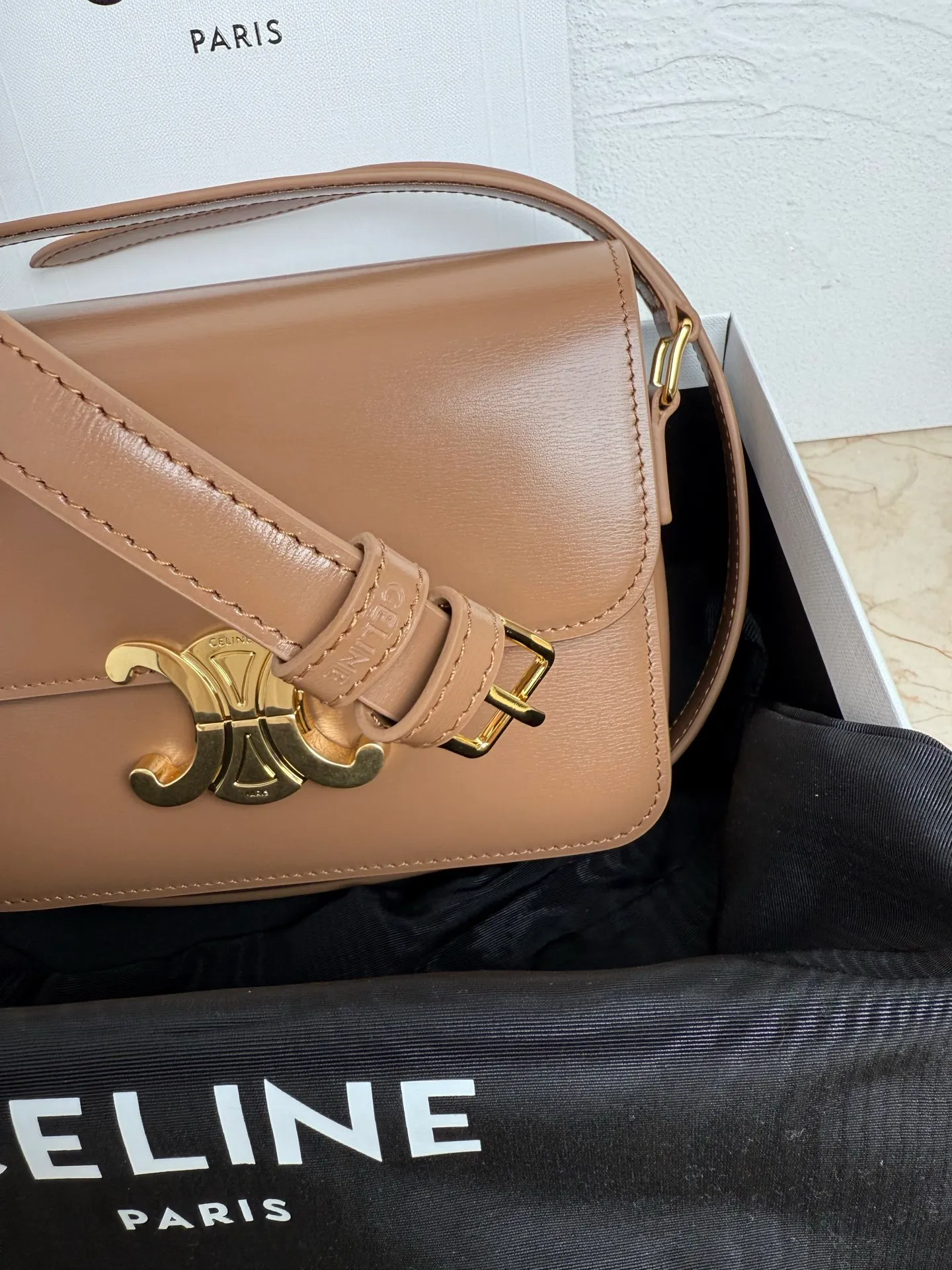p1560. TEEN TRIOMPHE calfskin handbag This small TRIOMPHE handbag in satin calfskin comes with an adjustable leather shoulder strap and TRIOMPHE exclusive buckle TRIOMPHE brass lock interior zip pocket and interior flat pocket Adjustable leather shoulder strap Length 17 inches (42 cm) 7 X 6 X 2 inches (18.5 X 14 X 6 cm) No.: 188423