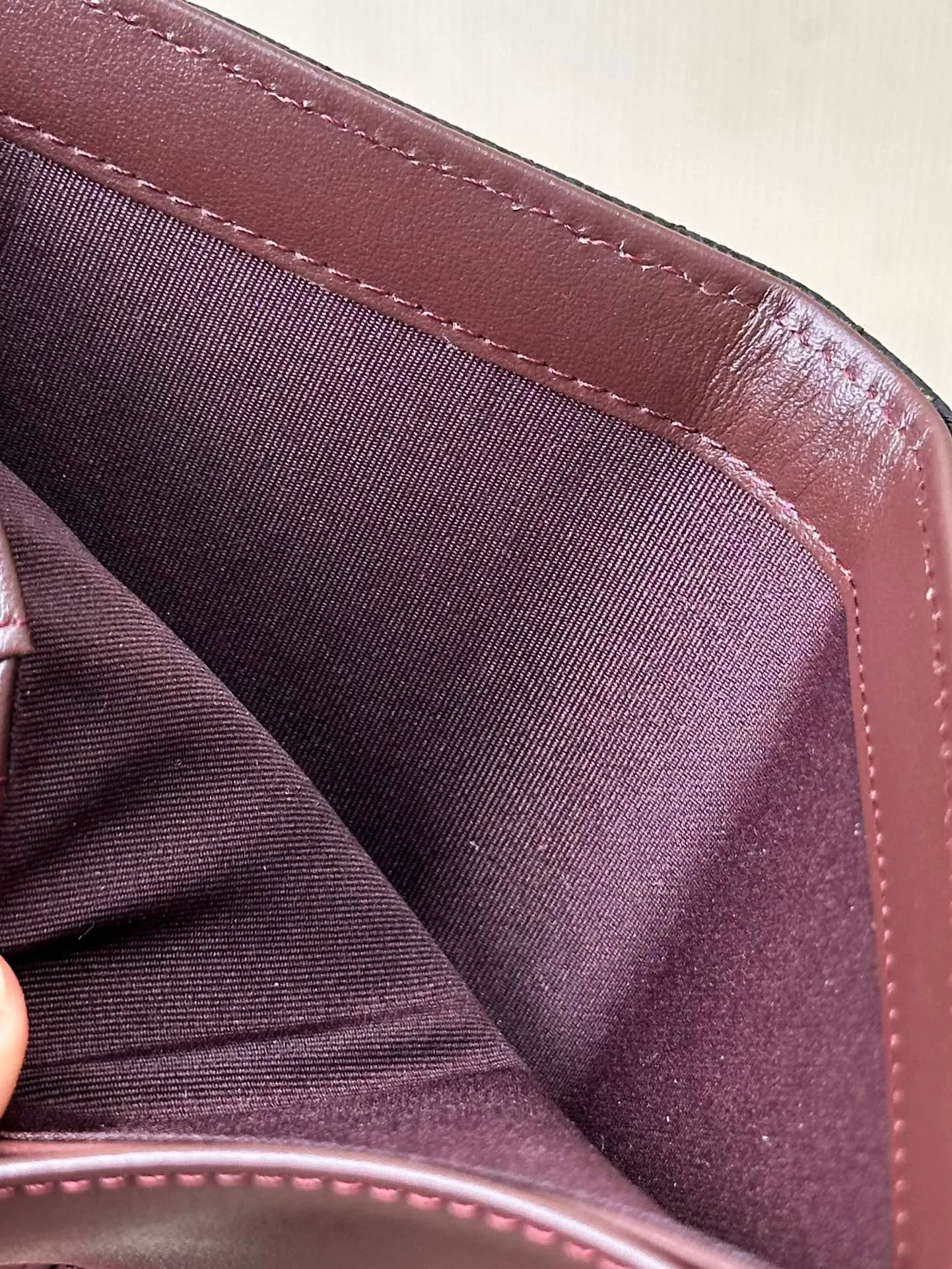 96066 The interior is made of burgundy calfskin. The leather has its own luster, and the texture is clear and delicate. It has various card slots on the side and an anti-counterfeiting code design on the inside.