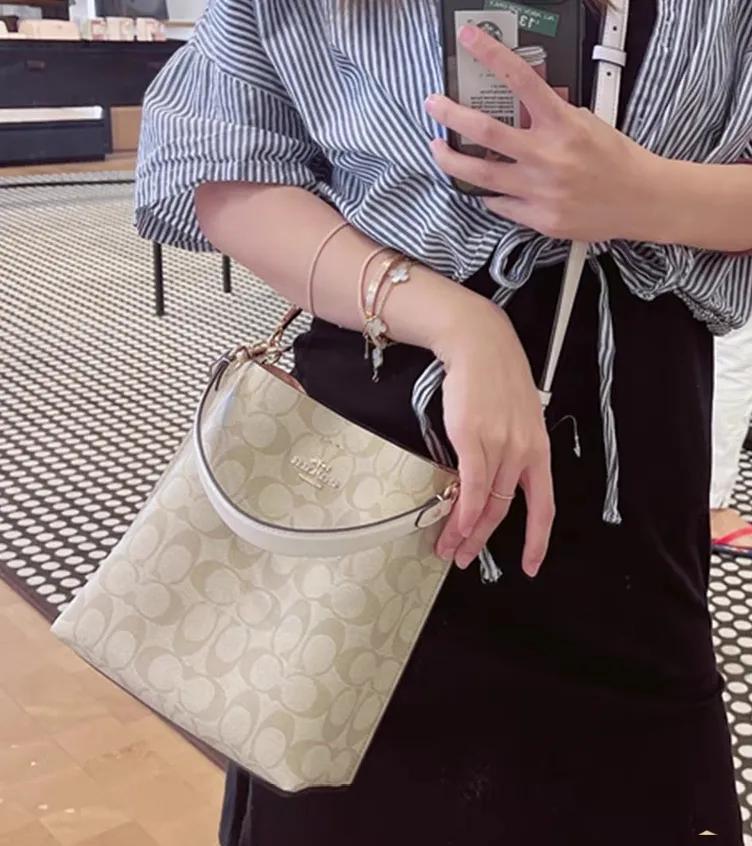 CA582, Coach's latest Mollie series bucket bag, small size, made of old PVC material and cowhide material. It is equipped with two detachable shoulder straps, long and short, which can be carried by hand or cross-body. There is a zipper compartment in the middle of the bag, which has good accommodation. The flat body of the bag is more comfortable on the upper body. Size:22*20*10cm
