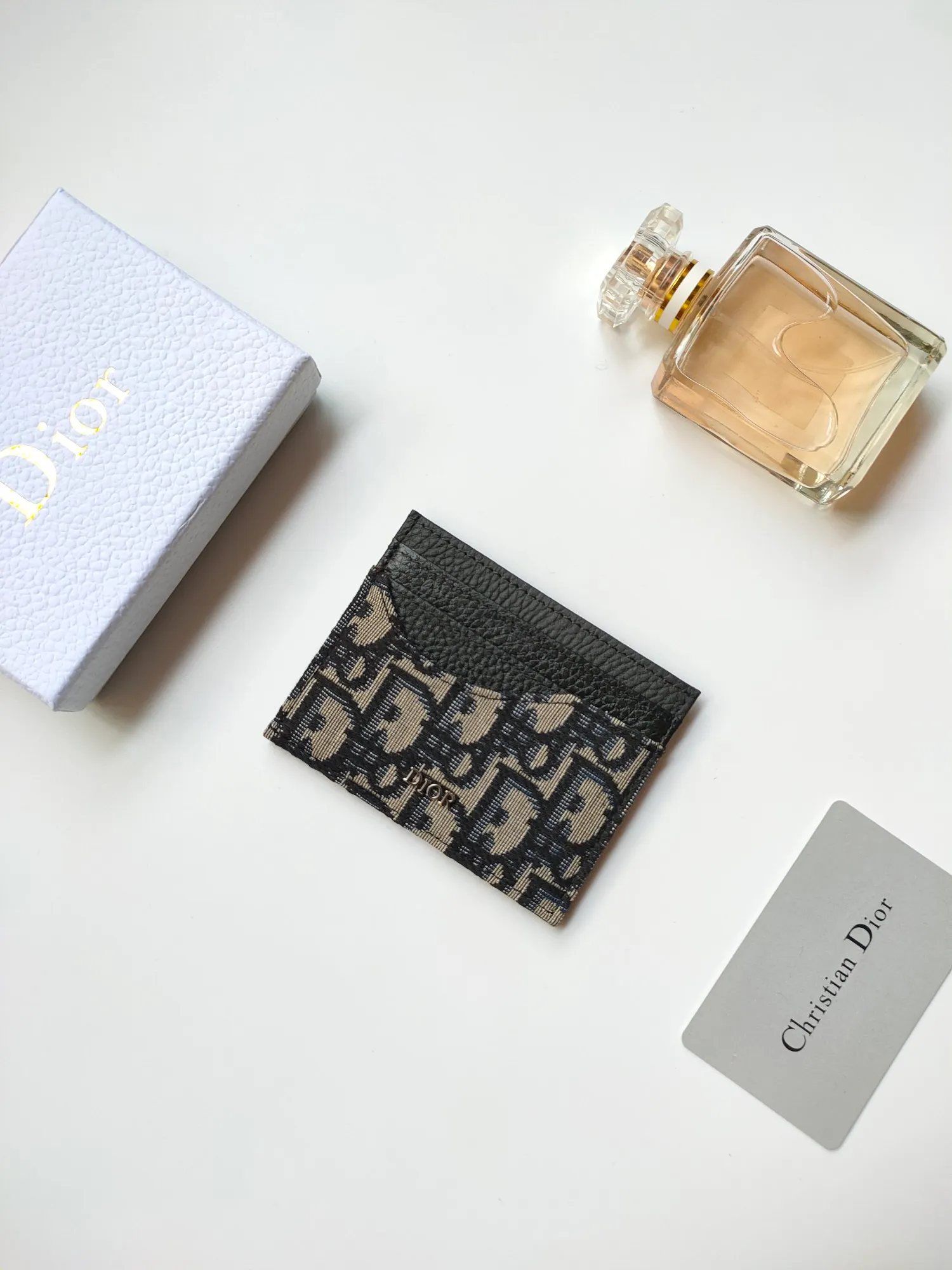 ￥90😍Dior’s new saddle card holder is an elegant accessory that showcases Dior’s exquisite craftsmanship. Style: CH164 Crafted from black grained calf leather with beige and black Oblique printed fabric details, it highlights the classic silhouette of the saddle series. It has three card slots on each side and one card slot on the top to store a variety of personal items. Elegantly styled with a metal-clad brass Dior signature on the front, it fits easily into any pocket. Size:10*8cm