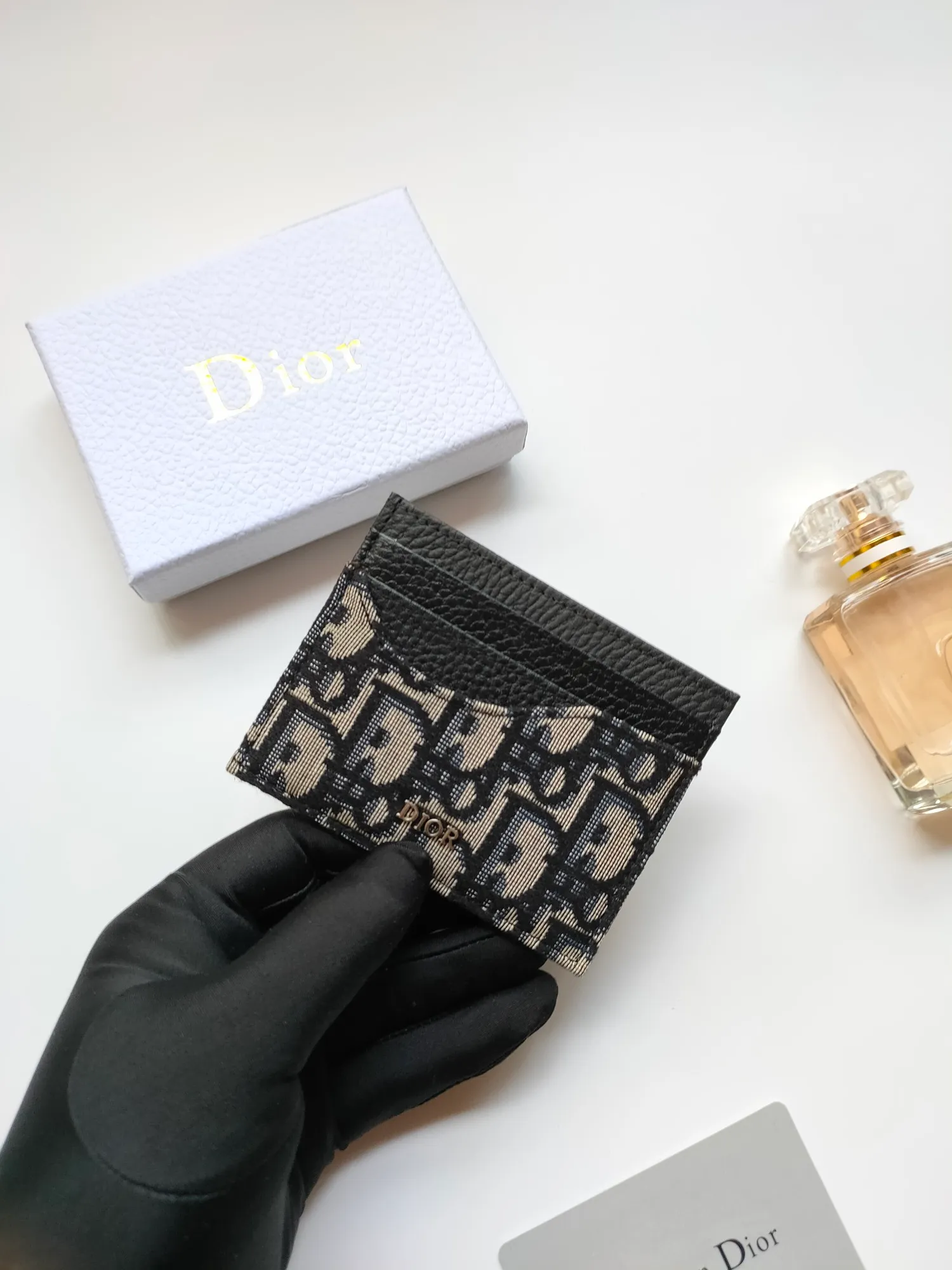 ￥90😍Dior’s new saddle card holder is an elegant accessory that showcases Dior’s exquisite craftsmanship. Style: CH164 Crafted from black grained calf leather with beige and black Oblique printed fabric details, it highlights the classic silhouette of the saddle series. It has three card slots on each side and one card slot on the top to store a variety of personal items. Elegantly styled with a metal-clad brass Dior signature on the front, it fits easily into any pocket. Size:10*8cm