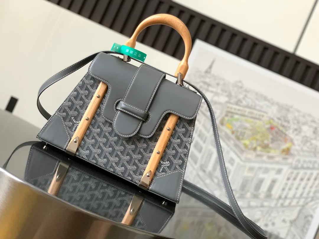 The P1700 original Saïgon bag is one of the signature pieces of the House of Goyard, embodying all the characteristic elements of the brand's boxmaking craftsmanship, such as wood, strips, leather corners and box-making nails. The Saigon Small Bag features a structured design and a removable shoulder strap for a chic and elegant look.  20 cm x 12 cm x 28 cm 🔎LAR 020186-Grey