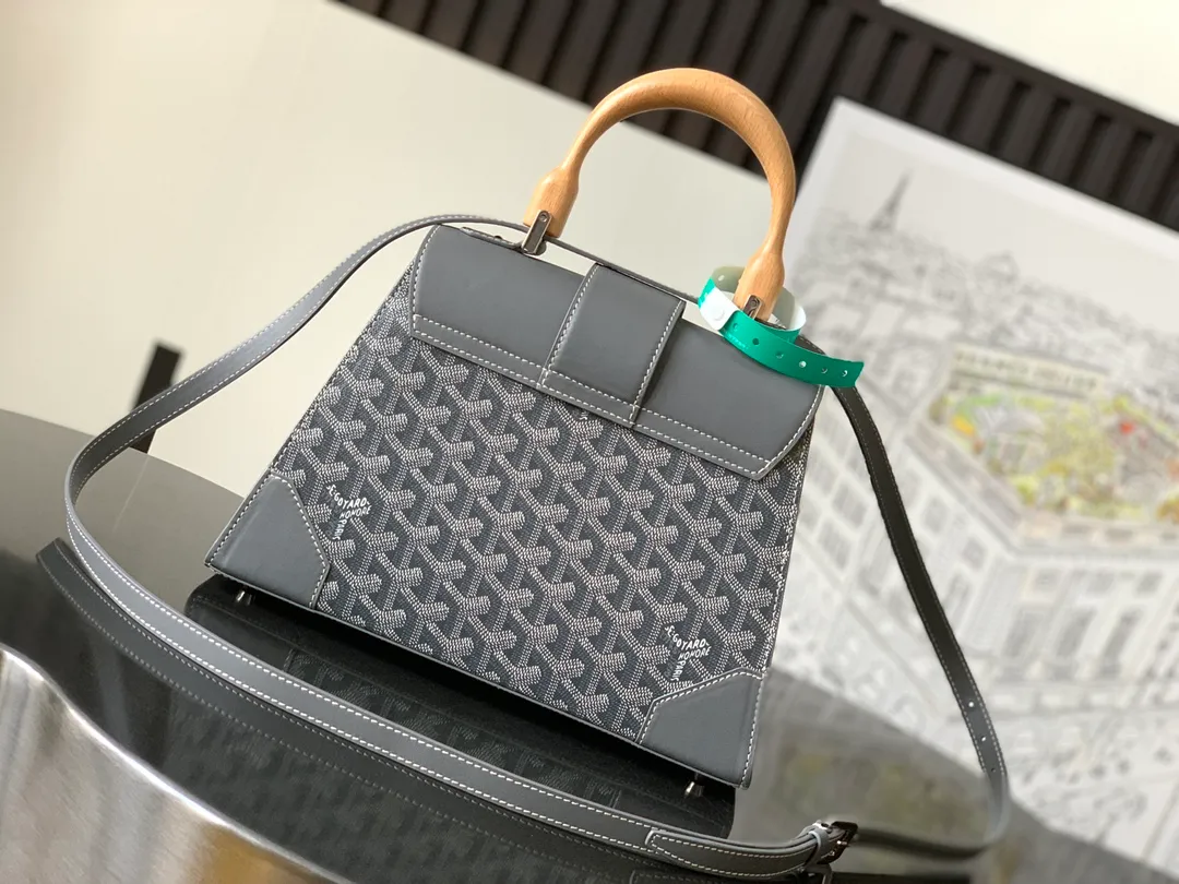 The P1700 original Saïgon bag is one of the signature pieces of the House of Goyard, embodying all the characteristic elements of the brand's boxmaking craftsmanship, such as wood, strips, leather corners and box-making nails. The Saigon Small Bag features a structured design and a removable shoulder strap for a chic and elegant look.  20 cm x 12 cm x 28 cm 🔎LAR 020186-Grey