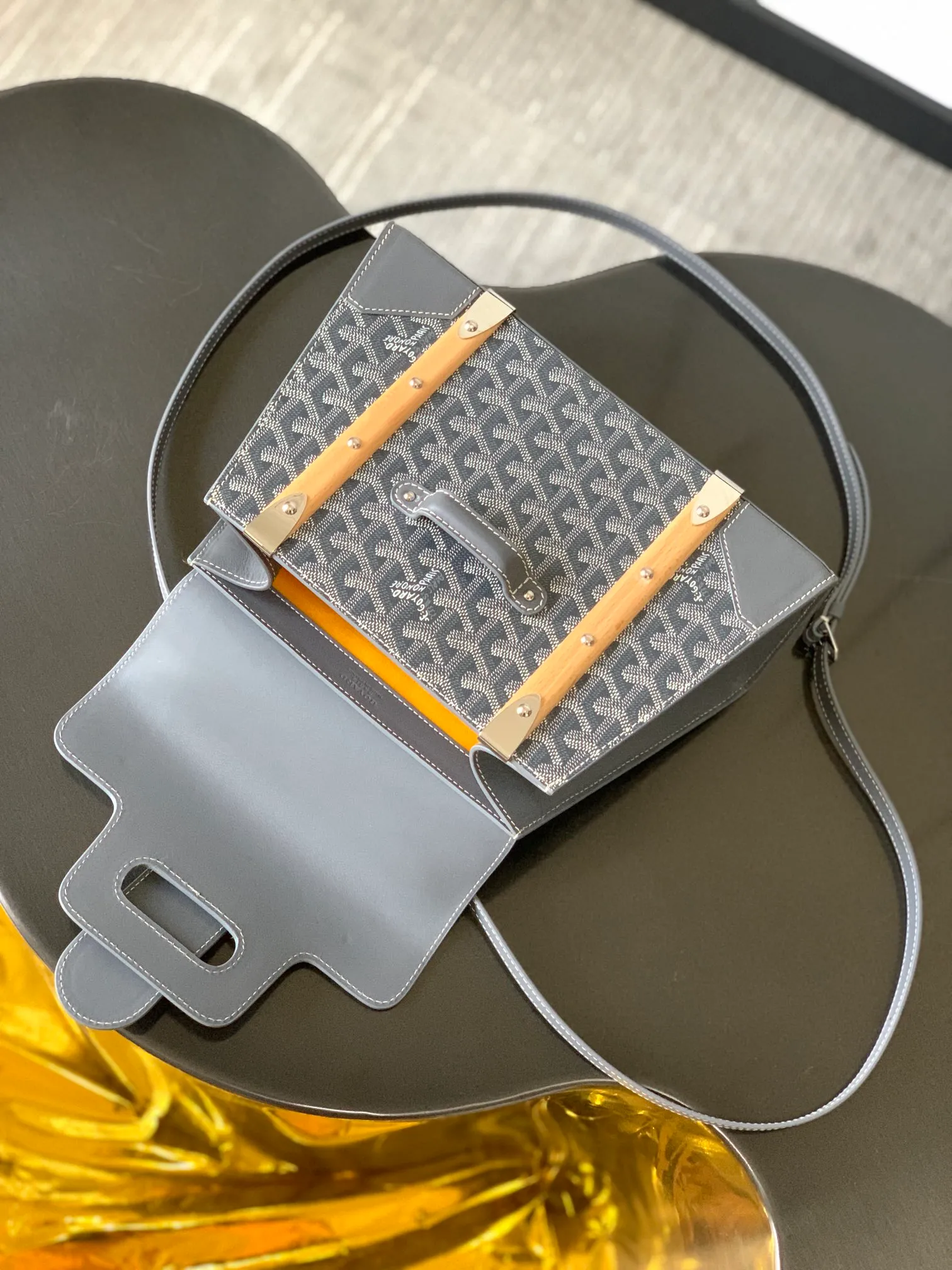 The P1700 original Saïgon bag is one of the signature pieces of the House of Goyard, embodying all the characteristic elements of the brand's boxmaking craftsmanship, such as wood, strips, leather corners and box-making nails. The Saigon Small Bag features a structured design and a removable shoulder strap for a chic and elegant look.  20 cm x 12 cm x 28 cm 🔎LAR 020186-Grey
