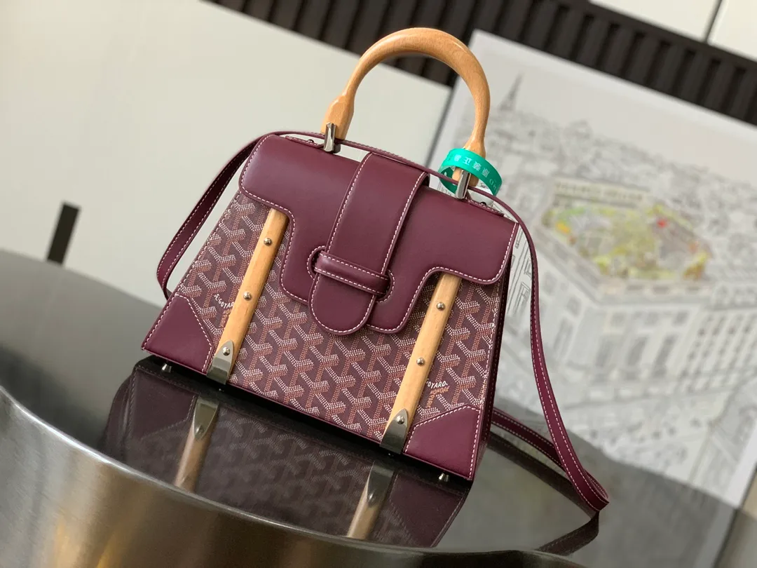 P1700 original.  The Saïgon bag is one of the iconic pieces of the House of Goyard, embodying all the characteristic elements of the brand's boxmaking craftsmanship, such as wood, strips, leather corners and tacks. The Saigon Small Bag features a structured design and a removable shoulder strap for a chic and elegant look.  20 cm x 12 cm x 28 cm 🔎LAR 020186-maroon