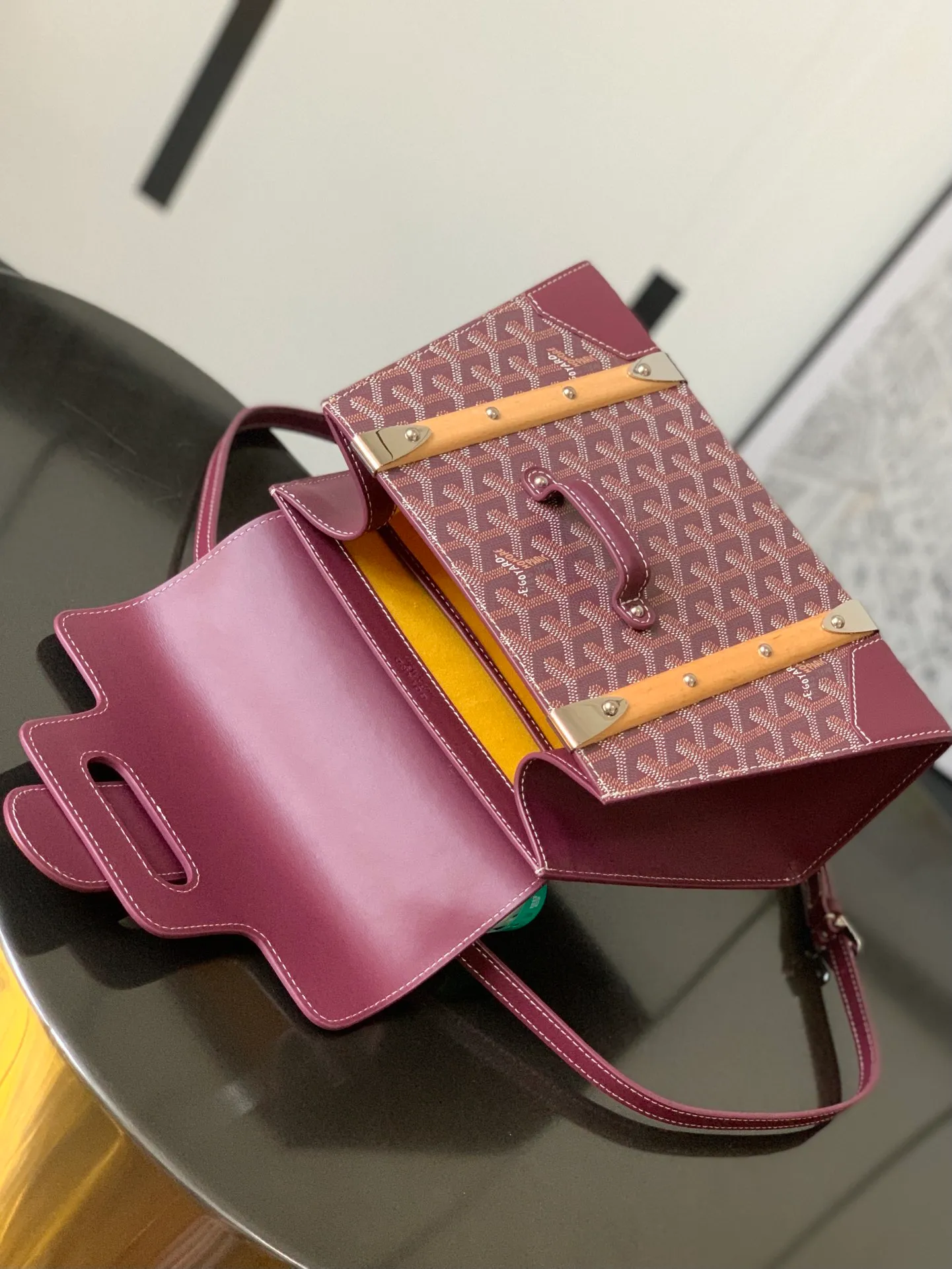 P1700 original.  The Saïgon bag is one of the iconic pieces of the House of Goyard, embodying all the characteristic elements of the brand's boxmaking craftsmanship, such as wood, strips, leather corners and tacks. The Saigon Small Bag features a structured design and a removable shoulder strap for a chic and elegant look.  20 cm x 12 cm x 28 cm 🔎LAR 020186-maroon
