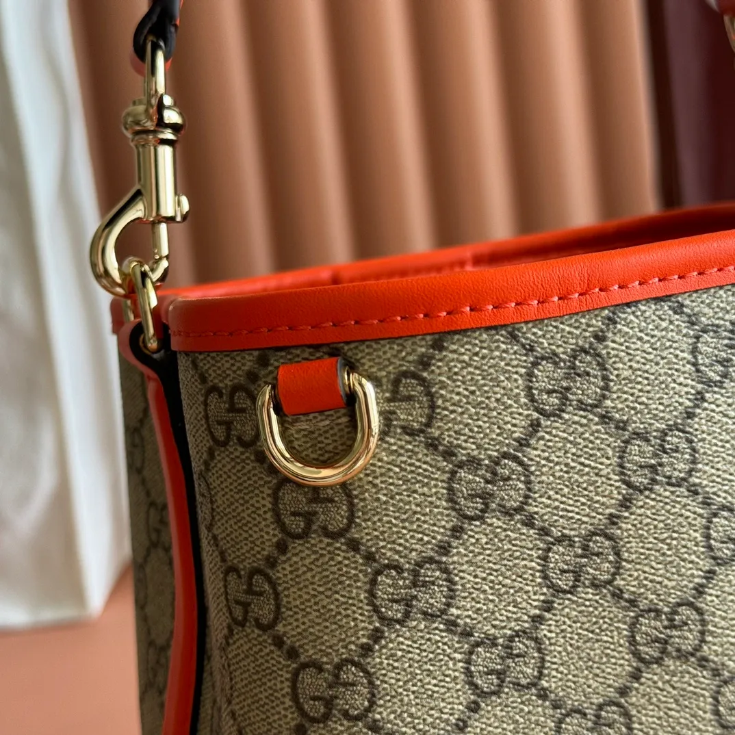 p920. 💋💋💋"With full set of original counter packaging" [New product] GG Emblem series reinterprets the brand's timeless elegance and exquisite craftsmanship. This bucket bag is lined in webbed cotton and features an internal compartment for added functionality. New GG monogram coated fabric in beige and dark brown Orange leather piping Light gold tone hardware Red and green web cotton lining The bag pictured is sold separately and does not come with the bag charm. Top handle with hook closure (height: 14 cm) Additional D-ring for attaching removable items Interior: two compartments and a central snap-stud compartment Removable and adjustable leather shoulder strap (height: 52 cm - 57.5 cm; length: 107 cm - 114 cm) Magnetic snap closure Ident.: 815118. Dimensions: 19 cm (width) x 18 cm (height) x 11 cm (depth) Weight: about 0.45 kg Color: brown orange pvc/original leather. Made in Italy