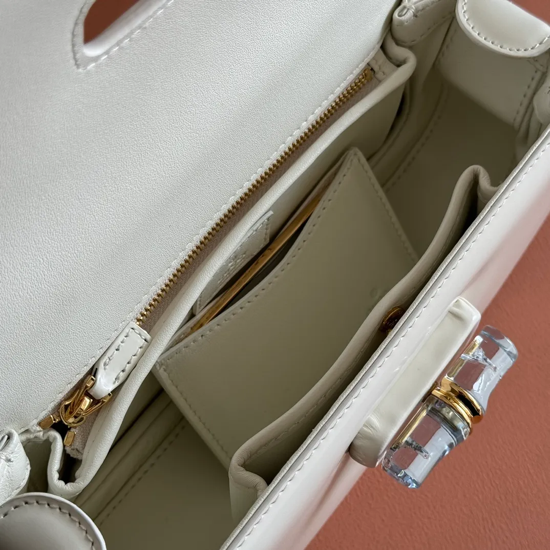 p1680. 💋💋💋 Equipped with full counter packaging [New Product] This small handbag reinterprets the iconic bamboo-shaped accessories with resin and brass details, adding another dazzling masterpiece to the 2025 spring and summer series. The Gucci Bamboo Diva tote adds a pop of color to any look. White glossy buffed leather Resin and brass bamboo hardware Three-level articulated compartments White leather lining Interior: One zippered pocket and a mirror with removable pocket Handle height 10cm Removable and adjustable leather shoulder strap (50cm high); length adjustable between 100cm and 116cm Bamboo lock Model number: 827750 Dimensions: 26.6cm (width) x 13cm (h) x 8 cm (depth) Weight: about 0.9 kg Color: white full leather/original leather. Made in Italy