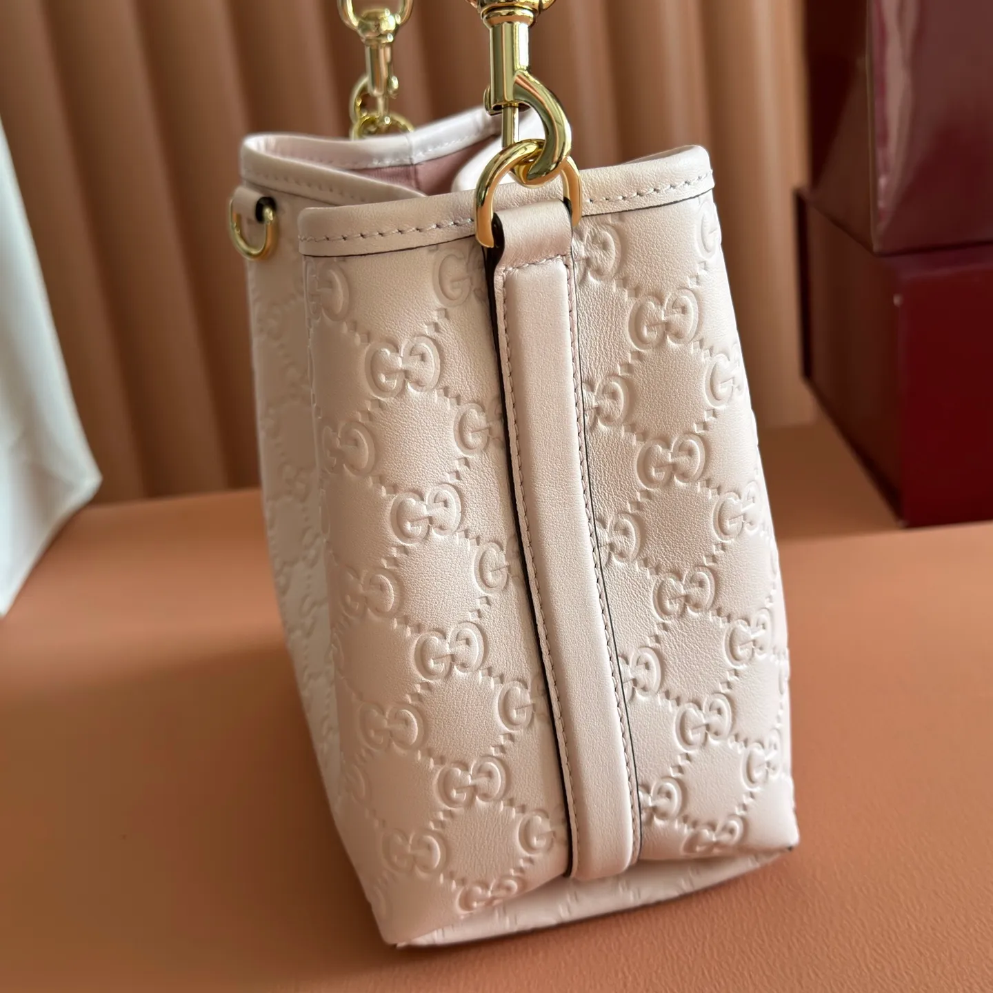 p1140. 💋💋💋【With full set of original counter packaging】GG Emblem series reinterprets the brand's timeless elegance and exquisite craftsmanship. Lined in webbed cotton, this bucket bag features an internal compartment for added functionality. Apricot pink GG printed embossed calf leather Light gold tone hardware Taupe cotton and linen lining Additional D-ring for attaching removable items Interior: two compartments and a central snap compartment Top handle with hook closure (height: 14 cm) Removable and adjustable calf leather shoulder strap (height: 52 cm - 57.5 cm; length: 107 cm - 114 cm) Magnetic snap closure Ident No.: 815118. Dimensions: 19cm (W) x 18cm (H) x 11cm (D) Weight: Approx. 0.45kg Color: Apricot Pink/Embossed. Made in Italy
