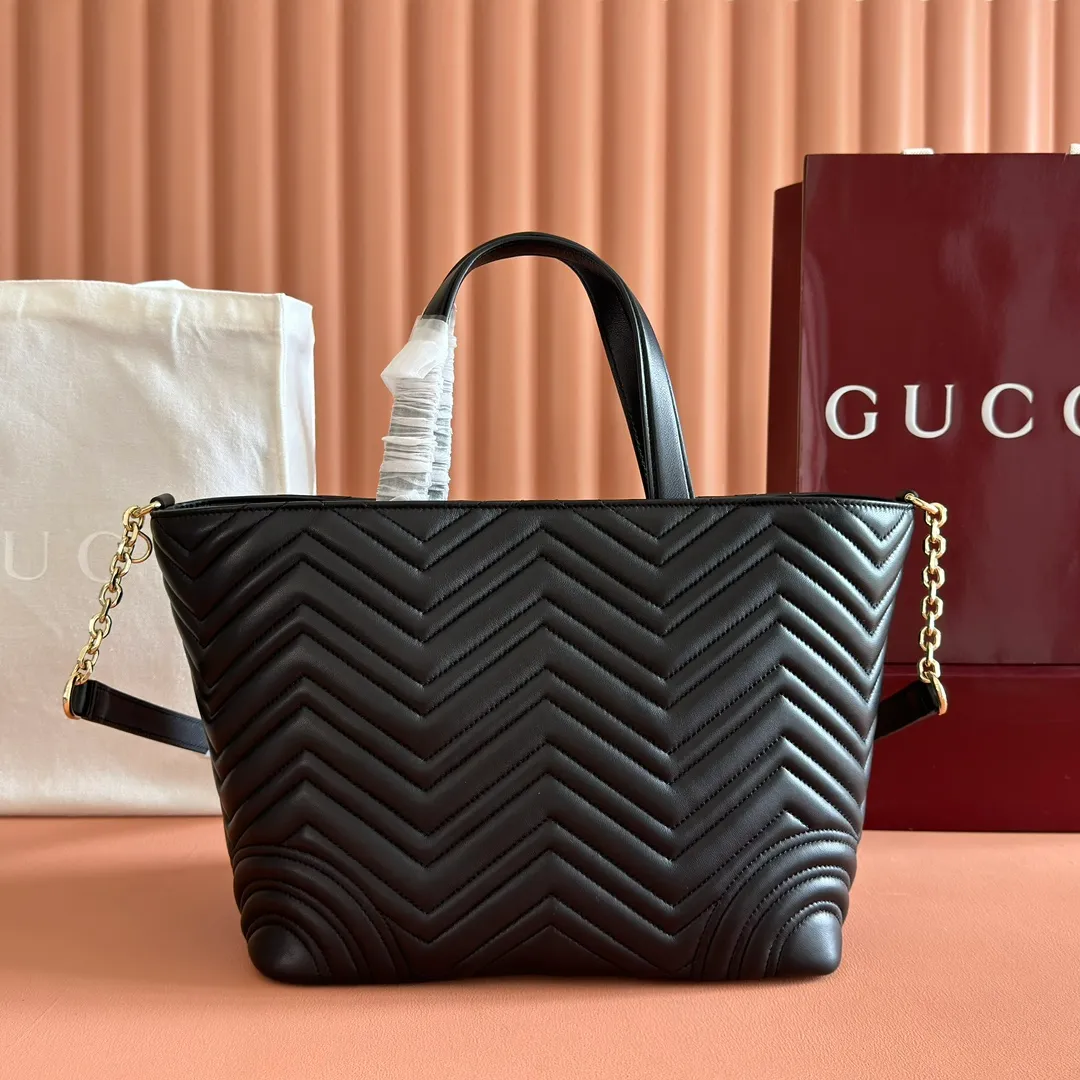 p1400. 💋💋💋 Comes with a complete set of original counter packaging [New product] This tote bag injects novel charm into the GG Marmont series with a new silhouette in the 2025 autumn and winter series. It can transform from a structural tote bag to a soft-lined bucket bag. The shape is paired with top handles and chain shoulder straps, presenting a variety of fashion styling options. Black V-shaped quilted sheepskin. Light gold-tone hardware. Gucci ankara red viscose lining. Double G. Interior: Zip pocket. Handle drop 14 cm. Shoulder strap drop 53 cm (bag closed: 48 cm). Ident.: 847387. Dimensions: 28cm (bottom width) x 39cm (top width) x 24cm (height) x 16cm (depth) Weight: approx. 0.7kg Colour: Black sheepskin. Made in Italy