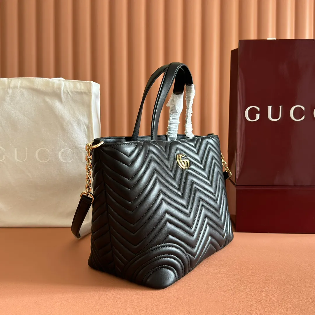 p1400. 💋💋💋 Comes with a complete set of original counter packaging [New product] This tote bag injects novel charm into the GG Marmont series with a new silhouette in the 2025 autumn and winter series. It can transform from a structural tote bag to a soft-lined bucket bag. The shape is paired with top handles and chain shoulder straps, presenting a variety of fashion styling options. Black V-shaped quilted sheepskin. Light gold-tone hardware. Gucci ankara red viscose lining. Double G. Interior: Zip pocket. Handle drop 14 cm. Shoulder strap drop 53 cm (bag closed: 48 cm). Ident.: 847387. Dimensions: 28cm (bottom width) x 39cm (top width) x 24cm (height) x 16cm (depth) Weight: approx. 0.7kg Colour: Black sheepskin. Made in Italy
