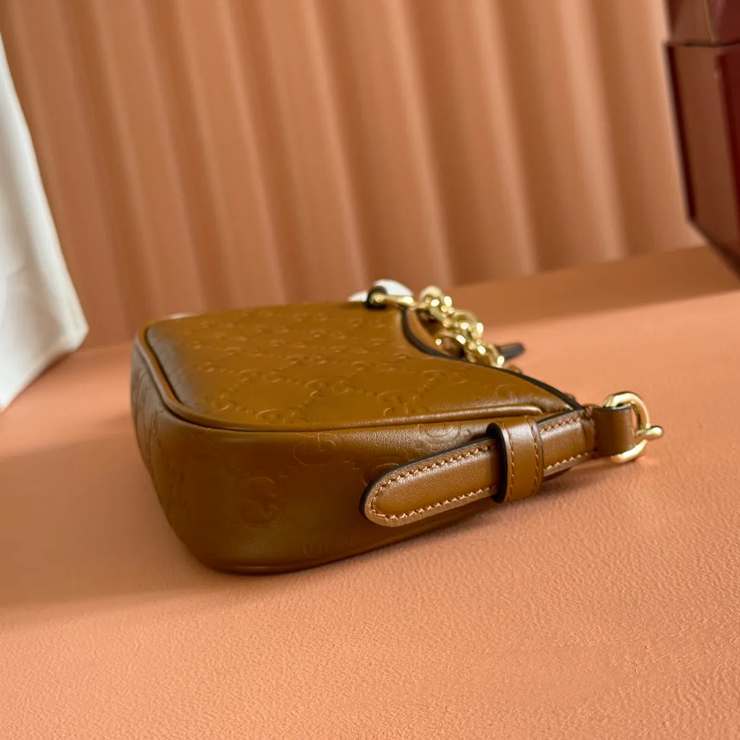 p900. 💋💋💋《With full set of original factory counter packaging》‼ ️【New Product】2025 Autumn and Winter Series, this small shoulder bag adopts a round silhouette with gold-tone accessories and chain straps, highlighting the style of the GG Emblem series. It features a zipper closure, an interior card pocket, and a cotton and linen lining for a refined feel. Gucci black (Rosso Ancora) GG printed embossed calf leather Gold tone accessories Gucci black (Rosso Ancora) cotton and linen lining The bag pictured is sold separately and does not come with the bag charm. Interior: card pocket, chain shoulder strap (23cm high), zipper closure. Model number: 847091. Dimensions: 19cm (bottom width) x 16.5cm (top width) 12cm (height) x 4cm (bottom depth) x 2.5cm (top depth) Weight: Approx. 0.211kg Color: Brown/Embossed. Made in Italy