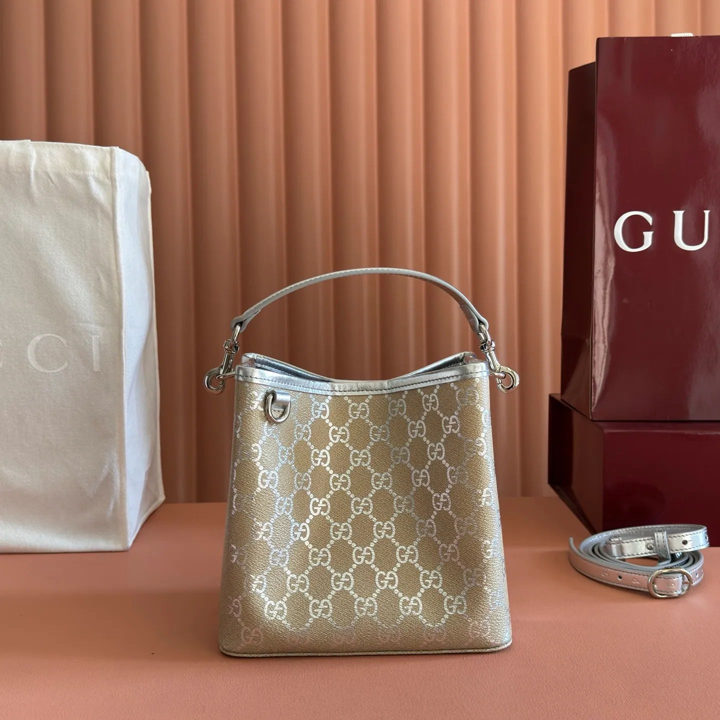 p940💋💋💋【Equipped with full set of original packaging at the counter】The GG Emblem series reinterprets the brand's enduring elegance and exquisite craftsmanship. It uses metallic styles to create a new interpretation of the iconic GG pattern, and is paired with metallic leather piping to complete the overall design. Light beige and silver metallic laminated-effect GG monogram coated fabric Silver metallic leather trim Silver-toned hardware Light gray cotton and linen lining Additional D-ring for attaching detachable items Interior: Two compartments and a central snap-stud compartment Top handle with hook closure (Height: 14cm) Removable and adjustable leather shoulder strap (Height: 52cm - 57.5cm; Length: 107cm - 114cm) Magnetic snap closure Model: 815118. Dimensions: 19cm (W) x 18cm (H) x 11cm (D) Weight: approx. 0.45kg Colour: Light Beige/Silver. Made in Italy