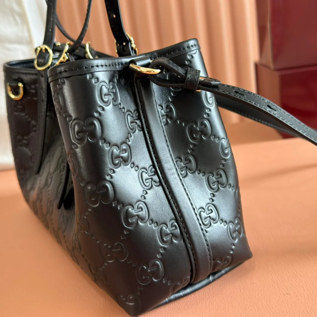 p1400. 💋💋💋Original leather configuration with full counter packaging [New product] GG Emblem series reinterprets the brand's timeless elegance and exquisite craftsmanship. Crafted in light pink, this small tote bag features adjustable handles with eyelets for an elegant look inspired by the equestrian world. Black GG Monogram coated fabric Black leather trim Light gold tone hardware Webbing cotton lining Additional D-ring for hanging removable items Adjustable handle with numbered eyelets; Height 18cm - 28cm Interior: 2 compartments and 1 central zippered compartment Adjustable leather shoulder strap (H 51.5cm - 57cm); length adjustable between 104cm and 114cm Magnetic snap closure Model: 815214. Dimensions: 30cm (width) x 18cm (height) x 11cm (depth) Weight: approx. 0.8kg Color: black pressed/original leather. Made in Italy