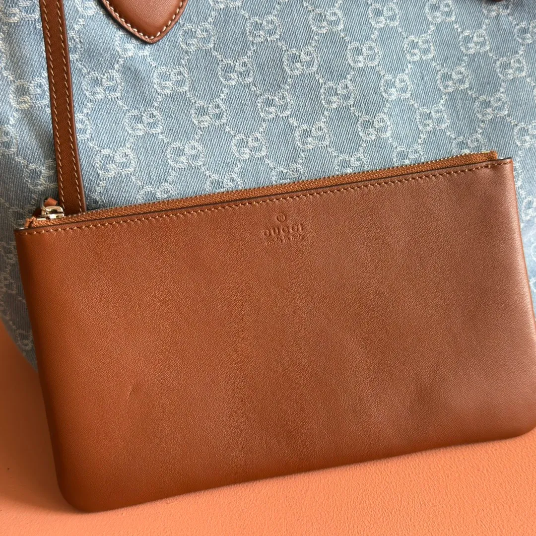Pre-order 💋💋💋【Equipped with counter gift bag】The Gucci Totissima series combines the word "tote" with the superlative word "issima" in Italian, highlighting the practical function and timeless background of this handbag. This medium tote bag comes with a removable clutch. Blue GG denim Brown leather trim with contrasting stitching Blue cotton and linen lining Detachable clutch: 21.5 cm (W) x 12.5 cm (H) Top handle (21 cm H) Model: 820481. Dimensions: 30.5cm (width) x 28cm (height) x 27cm (depth) Color: Gray denim/original leather. Weight: approx. 0.6kg Made in Italy