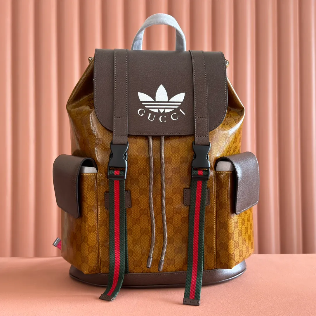 p1300. 📣📣📣【Original leather cabinet complete package】🔥🔥 adidas x Gucci joint series backpack, as one of the adidas x Gucci joint series, this backpack is decorated with Gucci Trefoil print. Adidas and Gucci boldly explore a joint series. The webbing and GG monogram are cleverly combined with the white three stripes and clover logo. The collection is inspired by the creative director’s fond memories of the 1980s and 1990s, integrating the two brands’ rich heritage and iconic design languages ​​to shape the style. Beige and brown GG crystal canvas with Gucci Trefoil print, brown leather adidas x Gucci collection. Red and green webbing, cotton and linen lining. Model: 495563. Dimensions: 34(W) x 42(H) x 16cm(D) Color: Brown/Crystal Canvas co-branded. Made in Italy