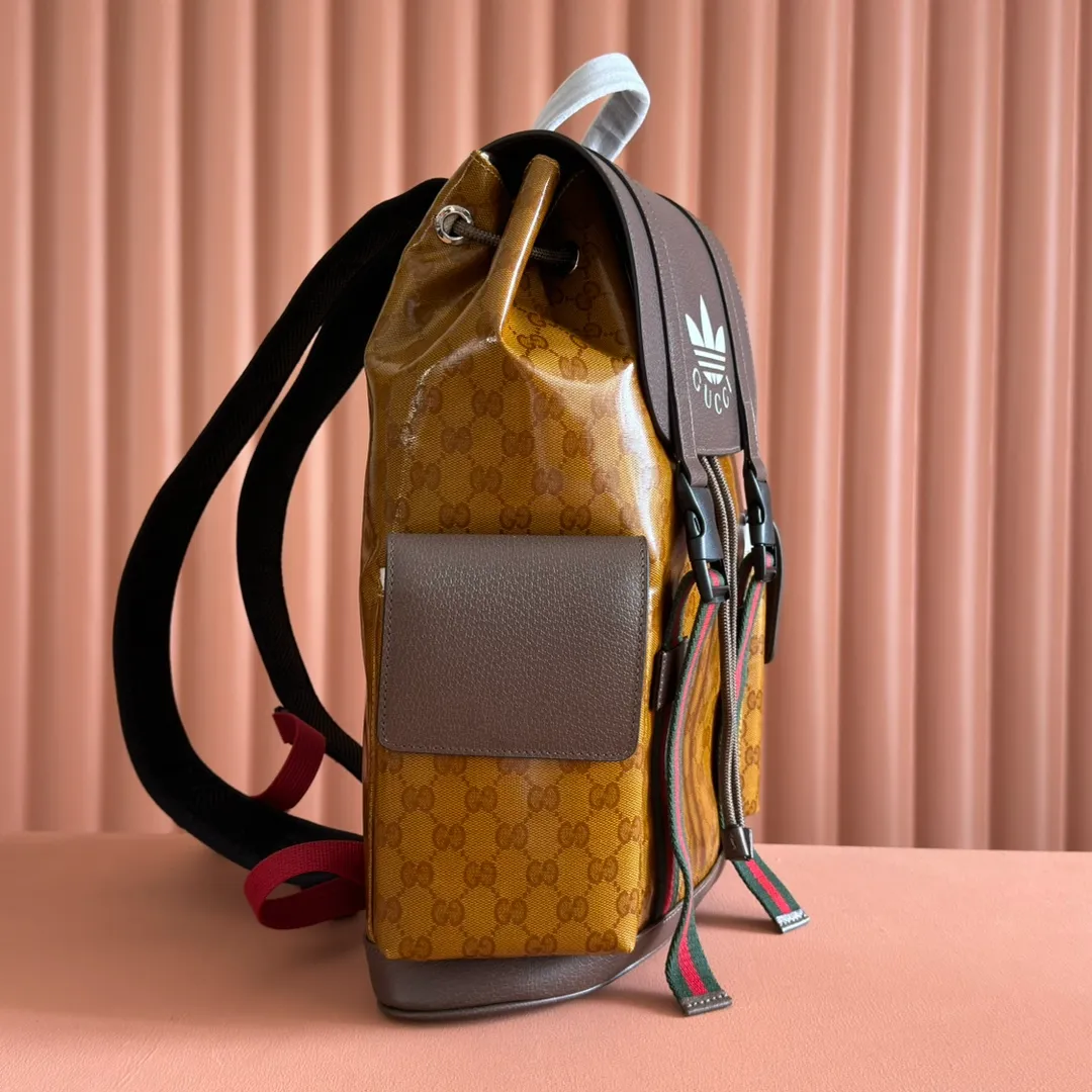 p1300. 📣📣📣【Original leather cabinet complete package】🔥🔥 adidas x Gucci joint series backpack, as one of the adidas x Gucci joint series, this backpack is decorated with Gucci Trefoil print. Adidas and Gucci boldly explore a joint series. The webbing and GG monogram are cleverly combined with the white three stripes and clover logo. The collection is inspired by the creative director’s fond memories of the 1980s and 1990s, integrating the two brands’ rich heritage and iconic design languages ​​to shape the style. Beige and brown GG crystal canvas with Gucci Trefoil print, brown leather adidas x Gucci collection. Red and green webbing, cotton and linen lining. Model: 495563. Dimensions: 34(W) x 42(H) x 16cm(D) Color: Brown/Crystal Canvas co-branded. Made in Italy