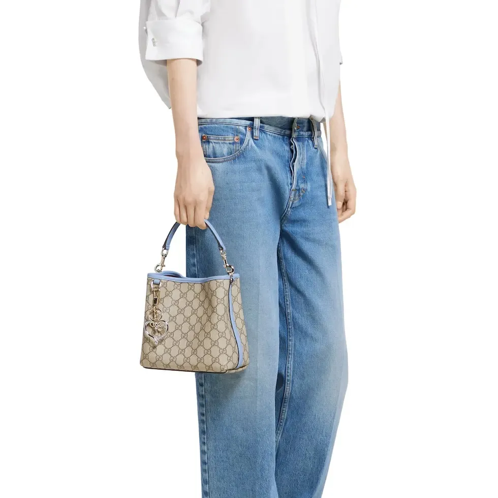 💕💕The GG Emblem series reinterprets the brand’s timeless elegance and exquisite craftsmanship. This bucket bag is lined in webbed cotton and features an internal compartment for added functionality. New GG monogram coated fabric in beige and dark brown Light blue leather trim Light gold tone hardware Red and green web cotton lining The bag pictured is sold separately and does not come with the bag charm. Top handle with hook closure (height: 14 cm) Additional D-ring for attaching removable items Interior: two compartments and a central snap-stud compartment Removable and adjustable leather shoulder strap (height: 52 cm - 57.5 cm; length: 107 cm - 114 cm) Magnetic snap closure Ident.: 815118. Dimensions: 19 cm (width) x 18 cm (height) x 11 cm (depth) Weight: about 0.45 kg Color: brown pvc/original leather. Made in Italy