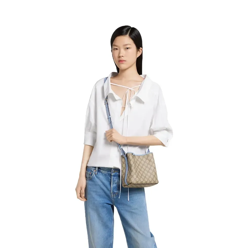 💕💕The GG Emblem series reinterprets the brand’s timeless elegance and exquisite craftsmanship. This bucket bag is lined in webbed cotton and features an internal compartment for added functionality. New GG monogram coated fabric in beige and dark brown Light blue leather trim Light gold tone hardware Red and green web cotton lining The bag pictured is sold separately and does not come with the bag charm. Top handle with hook closure (height: 14 cm) Additional D-ring for attaching removable items Interior: two compartments and a central snap-stud compartment Removable and adjustable leather shoulder strap (height: 52 cm - 57.5 cm; length: 107 cm - 114 cm) Magnetic snap closure Ident.: 815118. Dimensions: 19 cm (width) x 18 cm (height) x 11 cm (depth) Weight: about 0.45 kg Color: brown pvc/original leather. Made in Italy