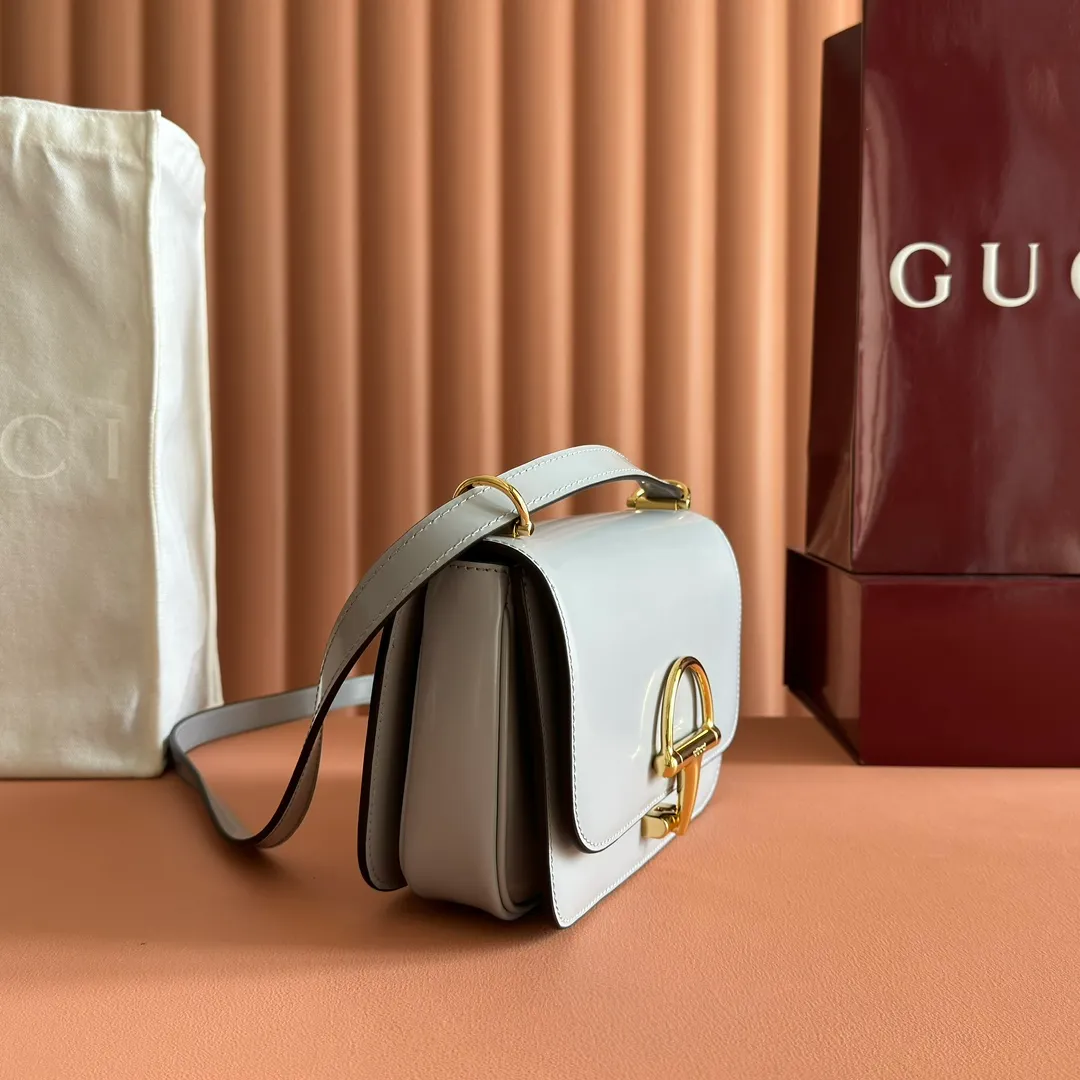 p1640. 💋💋💋【With full set of original counter packaging】2025 autumn and winter series, the Gucci Siena series small shoulder bag continues the evolution of the iconic element of Gucci's classic horsebit. Crafted from fine glossy leather, this shoulder bag has a structured shape and a half-horsebit buckle design from the 1970s. Finished with gold-tone hardware, the interior is lined with three levels of gusseting and a zipped pocket. Black fine glossy leather Gold-tone hardware Black leather lining Interior: 3-level fastening and 1 zipped pocket Shoulder straps: Height: 23cm – 25cm; Length: 127cm Half-horsebit snap fastener Ident: 846705. Dimensions: 22.5cm (width) x 14cm (height) x 8cm (depth) Weight: approx. 0.7kg Color: Gray full leather. Made in Italy