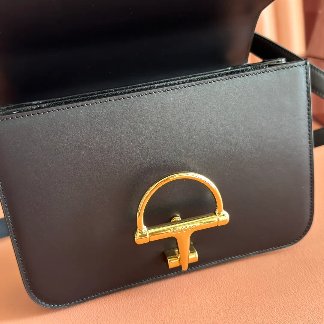 p1640. 💋💋💋【With full set of original counter packaging】2025 autumn and winter series, the Gucci Siena series small shoulder bag continues the evolution of the iconic element of Gucci's classic horsebit. Crafted from fine glossy leather, this shoulder bag has a structured shape and a half-horsebit buckle design from the 1970s. Finished with gold-tone hardware, the interior is lined with three levels of gusseting and a zipped pocket. Black fine glossy leather Gold-tone hardware Black leather lining Interior: 3-level fastening and 1 zipped pocket Shoulder straps: Height: 23cm – 25cm; Length: 127cm Half-horsebit snap fastener Ident: 846705. Dimensions: 22.5cm (width) x 14cm (height) x 8cm (depth) Weight: approx. 0.7kg Color: Black full leather. Made in Italy