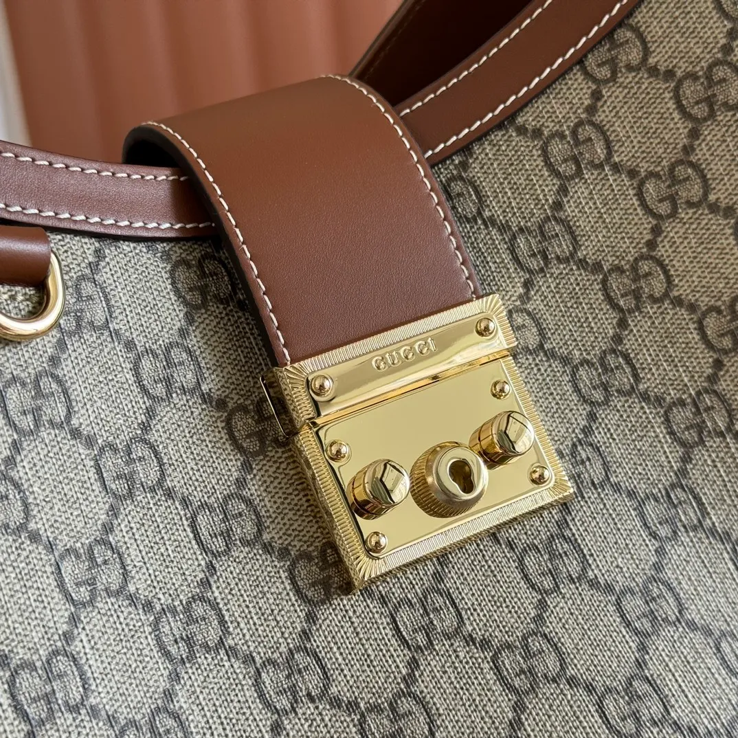 p1120💋💋💋【Full set of packaging at the counter】The Padlock series has launched a variety of fashionable bags with various carrying methods, adding color to the 2025 early autumn series. This shoulder bag features a central compartment with a zip pocket and is lined with webbing, reminiscent of the brand's signature pattern. Beige and dark brown GG monogram coated fabric Brown leather trim Light gold tone hardware Red and green web cotton lining Interior: Middle compartment with zip pocket Adjustable shoulder strap (44 cm high) Padlock closure with leather keychain Ref.: 839021. Dimensions: 29 cm (width) x 23.5 cm (height) x 15.5 cm (depth) Weight: about 0.75 kg Color: Brown PVC/original leather. Made in Italy