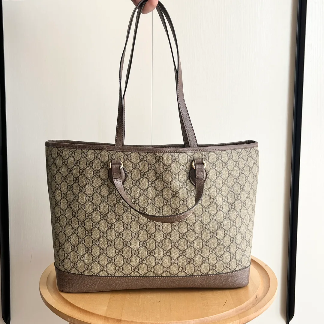 Actual shot #💰300 Model: 739730 Size: 38.5x28.5x15cm The GG Ophidia series is still one of Gucci’s iconic handbags. The brand launches new styles every season, creating versatile accessories that suit every look. Two handles give this tote a multi-functional character, allowing it to be worn as a shoulder bag or as a handbag. As a classic design element, the Double G has been deeply embedded in the brand's design. On this handbag, it is presented in a dazzling manner, contrasting with the GG Supreme canvas and brown leather piping.