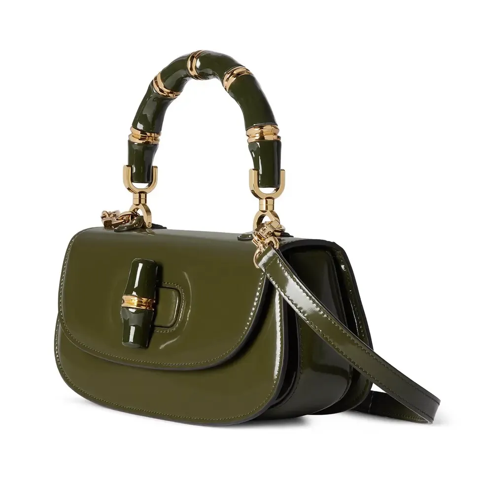 This small tote reinterprets the iconic bamboo accessory with enamel and brass details, adding another eye-catching addition to the Spring/Summer 2025 collection. Forest green glossy polished leather Bamboo enamel hardware with brass detail Three-level baffle compartments Forest green leather lining Interior: One zip pocket and mirror with removable pocket Handle height 10 cm Removable and adjustable leather shoulder strap (50 cm high); length adjustable between 100 cm and 116 cm Bamboo lock closure Ident: 827750. Dimensions: 26.6 cm (width) x 13 cm (height) x 8 cm (depth) Weight: approximately 0.9 kg Color: Forest green leather/original leather. Made in Italy