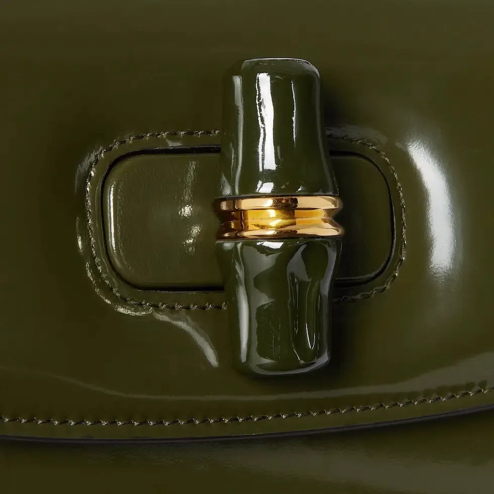 This small tote reinterprets the iconic bamboo accessory with enamel and brass details, adding another eye-catching addition to the Spring/Summer 2025 collection. Forest green glossy polished leather Bamboo enamel hardware with brass detail Three-level baffle compartments Forest green leather lining Interior: One zip pocket and mirror with removable pocket Handle height 10 cm Removable and adjustable leather shoulder strap (50 cm high); length adjustable between 100 cm and 116 cm Bamboo lock closure Ident: 827750. Dimensions: 26.6 cm (width) x 13 cm (height) x 8 cm (depth) Weight: approximately 0.9 kg Color: Forest green leather/original leather. Made in Italy