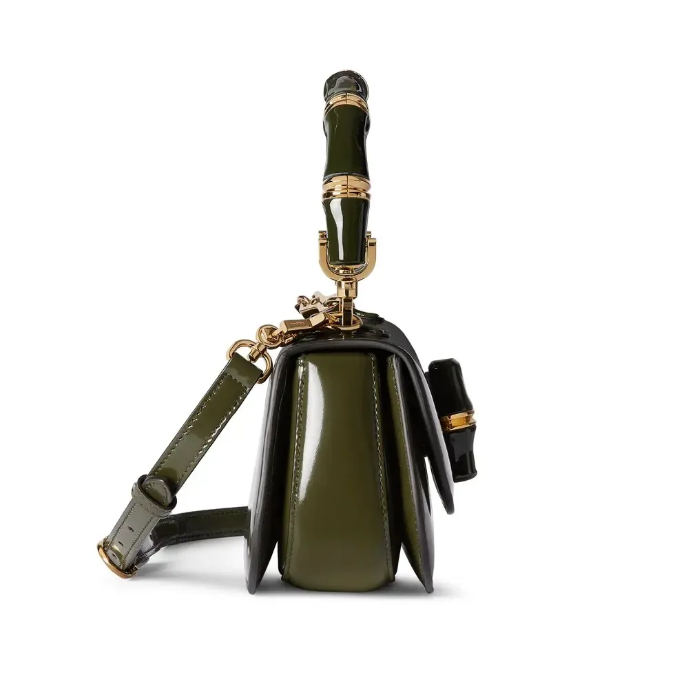 This small tote reinterprets the iconic bamboo accessory with enamel and brass details, adding another eye-catching addition to the Spring/Summer 2025 collection. Forest green glossy polished leather Bamboo enamel hardware with brass detail Three-level baffle compartments Forest green leather lining Interior: One zip pocket and mirror with removable pocket Handle height 10 cm Removable and adjustable leather shoulder strap (50 cm high); length adjustable between 100 cm and 116 cm Bamboo lock closure Ident: 827750. Dimensions: 26.6 cm (width) x 13 cm (height) x 8 cm (depth) Weight: approximately 0.9 kg Color: Forest green leather/original leather. Made in Italy