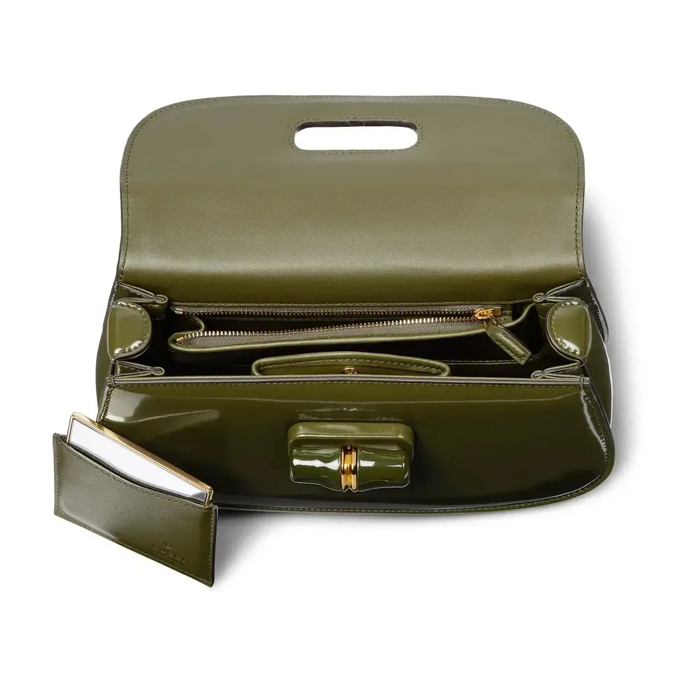 This small tote reinterprets the iconic bamboo accessory with enamel and brass details, adding another eye-catching addition to the Spring/Summer 2025 collection. Forest green glossy polished leather Bamboo enamel hardware with brass detail Three-level baffle compartments Forest green leather lining Interior: One zip pocket and mirror with removable pocket Handle height 10 cm Removable and adjustable leather shoulder strap (50 cm high); length adjustable between 100 cm and 116 cm Bamboo lock closure Ident: 827750. Dimensions: 26.6 cm (width) x 13 cm (height) x 8 cm (depth) Weight: approximately 0.9 kg Color: Forest green leather/original leather. Made in Italy