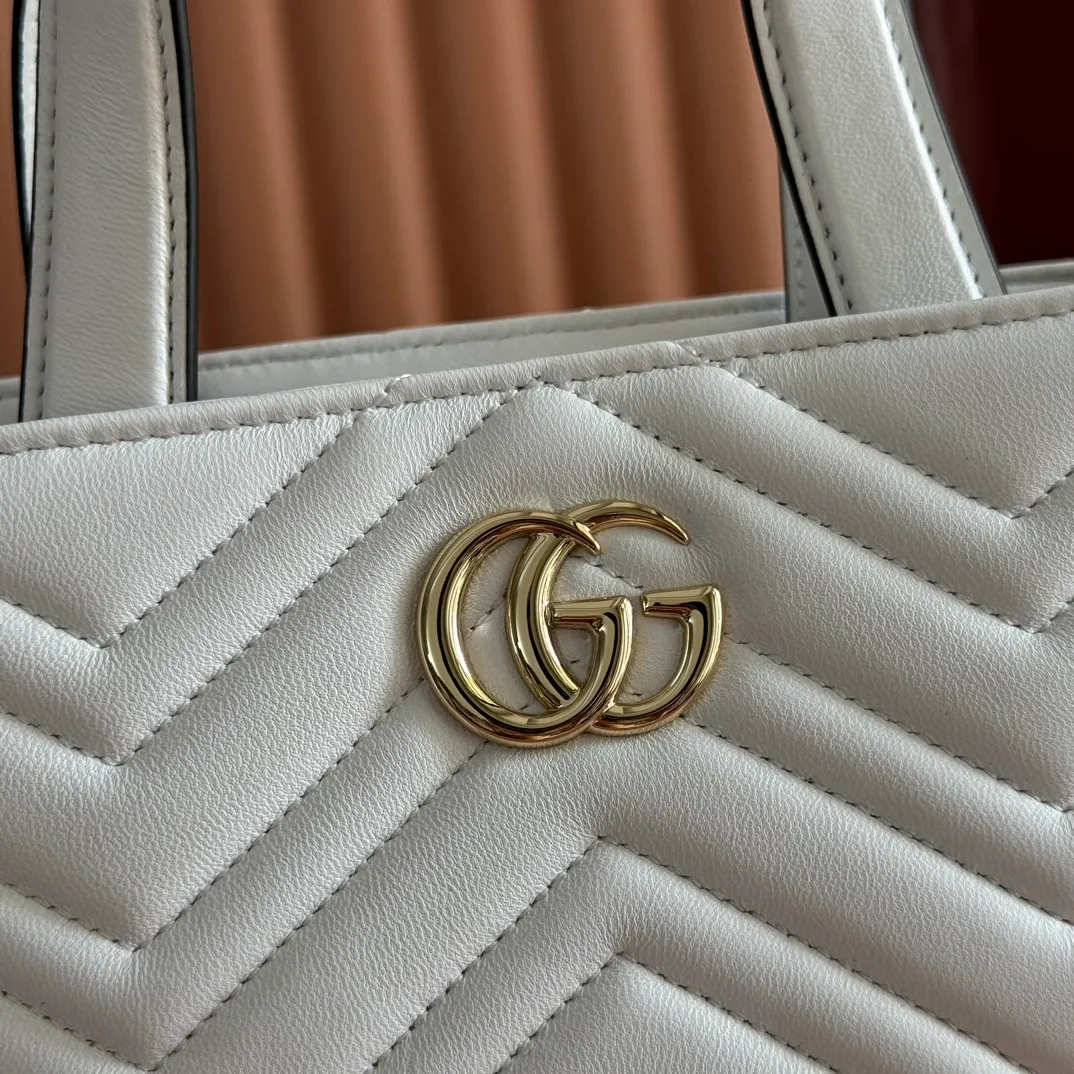 p1280. 💋💋💋 Comes with a complete set of original counter packaging [New product] This tote bag injects novel charm into the GG Marmont series with a new silhouette in the 2025 autumn and winter series. It can transform from a structural tote bag to a soft-lined bucket bag. The shape is paired with top handles and chain shoulder straps, presenting a variety of fashion styling options. White chevron quilted sheepskin Light gold-tone hardware Gucci ankara red viscose lining Double G Interior: Open pocket Handle drop 11 cm Shoulder strap drop 53 cm (bag closed: 45 cm) Ident.: 847386. Dimensions: 18cm (bottom width) x 29cm (top width) x 18cm (height) x 12.5cm (depth) Weight: approx. 0.4kg Color: White sheepskin. Made in Italy