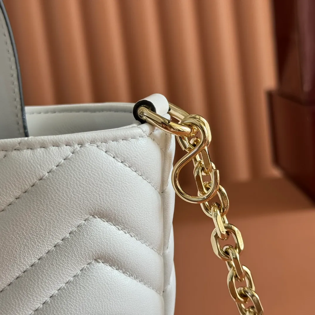 p1280. 💋💋💋 Comes with a complete set of original counter packaging [New product] This tote bag injects novel charm into the GG Marmont series with a new silhouette in the 2025 autumn and winter series. It can transform from a structural tote bag to a soft-lined bucket bag. The shape is paired with top handles and chain shoulder straps, presenting a variety of fashion styling options. White chevron quilted sheepskin Light gold-tone hardware Gucci ankara red viscose lining Double G Interior: Open pocket Handle drop 11 cm Shoulder strap drop 53 cm (bag closed: 45 cm) Ident.: 847386. Dimensions: 18cm (bottom width) x 29cm (top width) x 18cm (height) x 12.5cm (depth) Weight: approx. 0.4kg Color: White sheepskin. Made in Italy