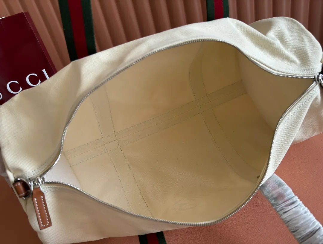 p1060. 💋💋💋"With a complete set of original counter gift bag packaging"💕[New Product] With the theme of freedom, vitality and community, the 2025 spring and summer series has newly presented a variety of travel items and men's bags, adding more fun to travel and exploration. This canvas travel bag features embellished stitching at the top, tonal leather piping and a 'Gucci Made in Italy' badge printed on the front. Off-white canvas Off-white leather trim "Gucci Made in Italy" and badge print Red and blue web Interior: 1 side handle Handle height: 24 cm Adjustable web canvas shoulder strap (55 cm high); length adjustable from 82 cm to 138 cm Zip closure Ident: 816866. Dimensions: 54cm (W) x 24cm (H) x 24cm (D) Weight: Approx. 0.985kg Colour: Off-white canvas. Made in Italy