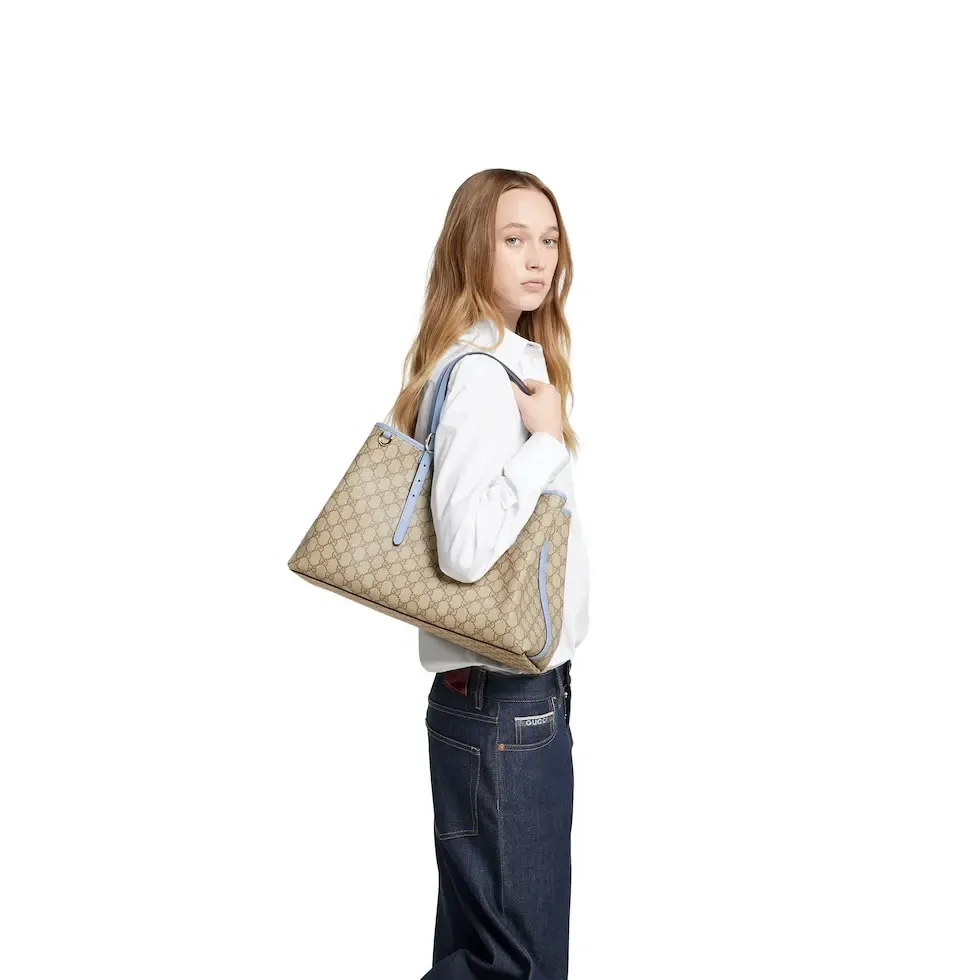 💕💕The GG Emblem series reinterprets the brand’s timeless elegance and exquisite craftsmanship. Inspired by the equestrian world, this tote bag features an adjustable top handle with numbered eyelets. New GG monogram coated fabric in beige and dark brown Light blue leather trim with contrast stitching Light gold tone hardware Red and green webbing cotton lining The bag pictured is sold separately and does not come with the bag charm. Also features D-ring for hanging removable items Adjustable handle with numbered eyelets (height: 21.5 cm - 31.5 cm) Interior: two compartments and one central zipped compartment Magnetic snap closure Ident.: 815213. Dimensions: 38cm (width) x 25cm (height) x 15cm (depth) Weight: about 0.85kg Color: brown pvc/original leather. Made in Italy