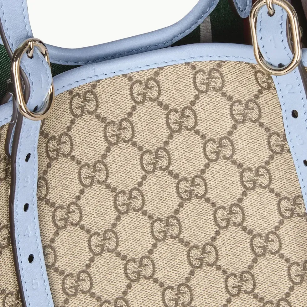 💕💕The GG Emblem series reinterprets the brand’s timeless elegance and exquisite craftsmanship. Inspired by the equestrian world, this tote bag features an adjustable top handle with numbered eyelets. New GG monogram coated fabric in beige and dark brown Light blue leather trim with contrast stitching Light gold tone hardware Red and green webbing cotton lining The bag pictured is sold separately and does not come with the bag charm. Also features D-ring for hanging removable items Adjustable handle with numbered eyelets (height: 21.5 cm - 31.5 cm) Interior: two compartments and one central zipped compartment Magnetic snap closure Ident.: 815213. Dimensions: 38cm (width) x 25cm (height) x 15cm (depth) Weight: about 0.85kg Color: brown pvc/original leather. Made in Italy