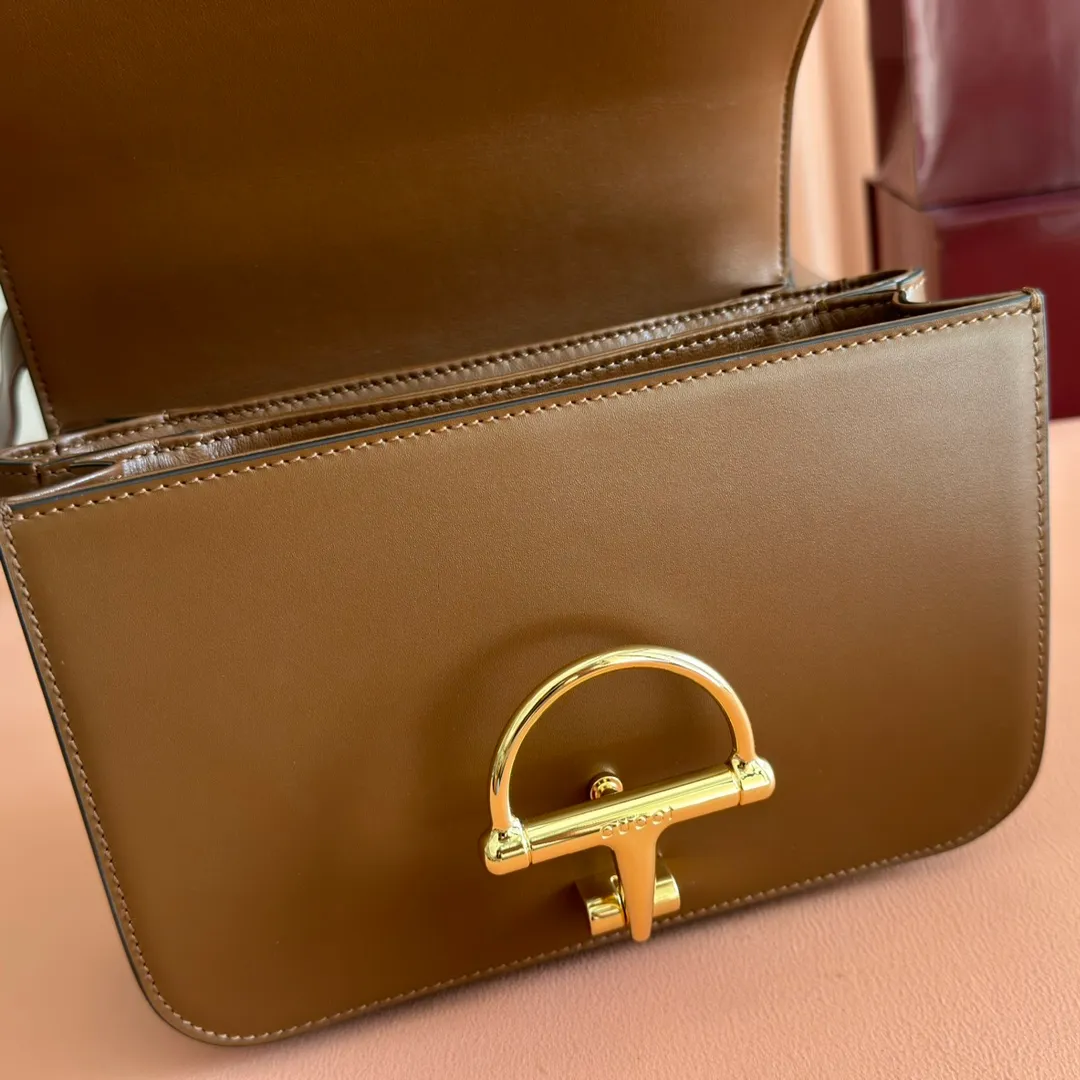 p1640. 💋💋💋【With full set of original counter packaging】2025 autumn and winter series, the Gucci Siena series small shoulder bag continues the evolution of the iconic element of Gucci's classic horsebit. Crafted from fine glossy leather, this shoulder bag has a structured shape and a half-horsebit buckle design from the 1970s. Finished with gold-tone hardware, the interior is lined with three levels of gusseting and a zipped pocket. Black fine glossy leather Gold-tone hardware Black leather lining Interior: 3-level fastening and 1 zipped pocket Shoulder straps: Height: 23cm – 25cm; Length: 127cm Half-horsebit snap fastener Ident: 846705. Dimensions: 22.5cm (width) x 14cm (height) x 8cm (depth) Weight: approx. 0.7kg Color: brown full leather. Made in Italy