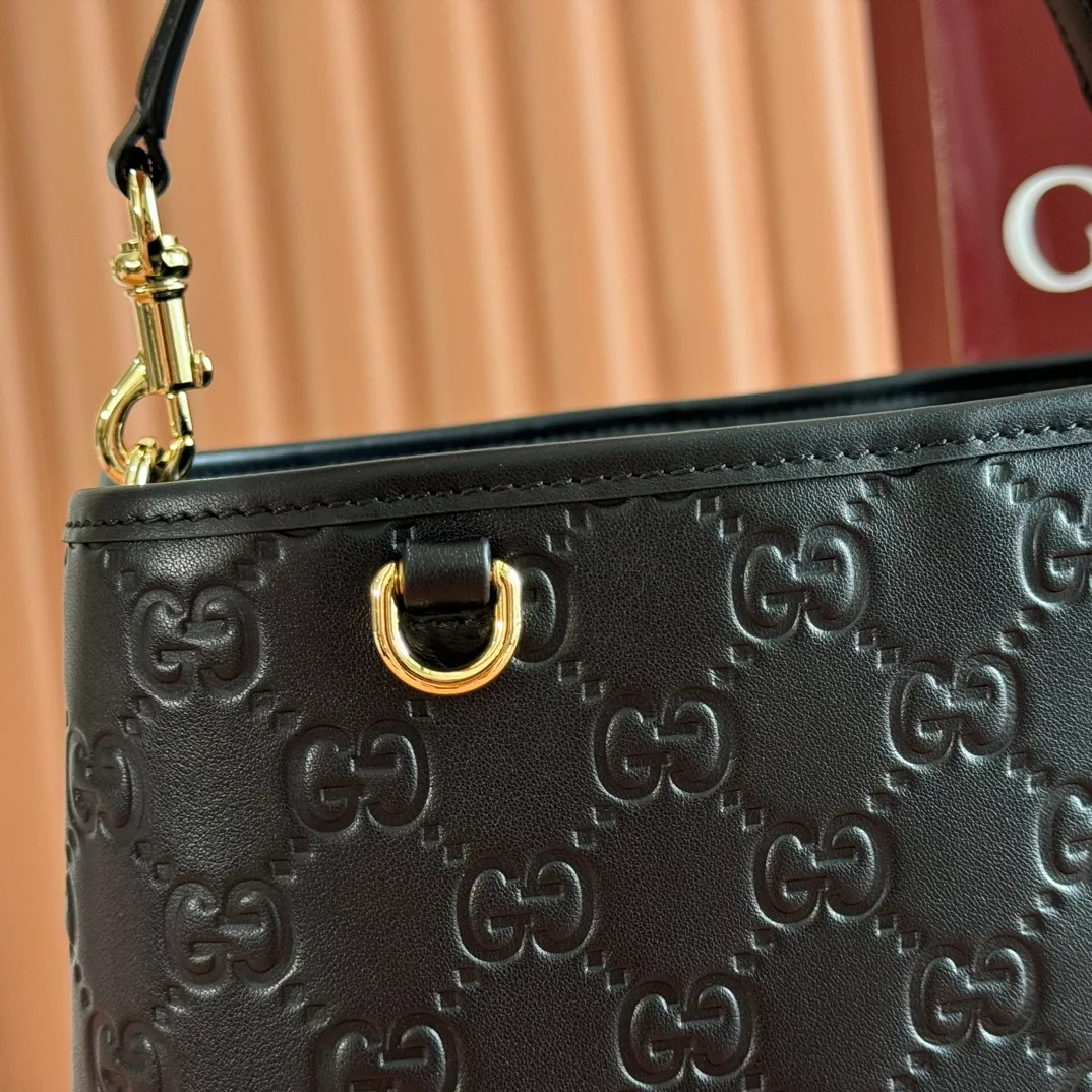 p1320. 💋💋💋Original leather configuration with full counter packaging [New product] GG Emblem series reinterprets the brand's timeless elegance and exquisite craftsmanship. Lined in webbed cotton, this bucket bag features an internal compartment for added functionality. Black GG printed embossed leather Light gold tone hardware Black cotton and linen blend lining Top handle with hook closure (height: 18cm) Additional D-ring for attaching removable items Interior: two compartments and a central snap-stud compartment Detachable and adjustable leather shoulder strap (height: 54cm - 60cm; length: 105cm - 115cm) Magnetic snap closure Weight: approx. 700g. Model: 815103. Dimensions: 25 cm (width) x 25 cm (height) x 15.5 cm (depth) Color: black embossed/original leather. Made in Italy