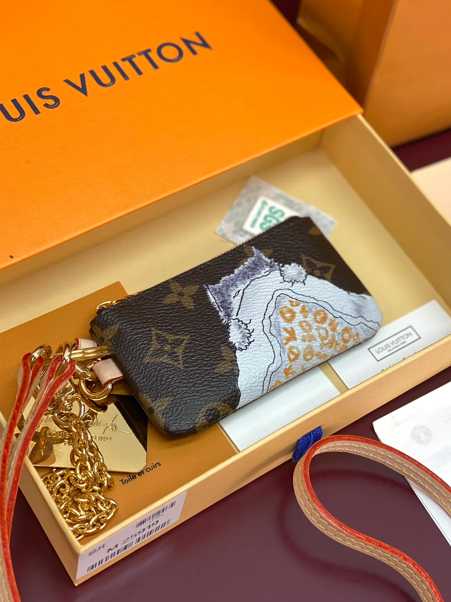 M25919 silk screen cat! Mobile Phone Charm This mobile phone charm showcases fashion icon Grace Coddington's love for cats with a hand-drawn pattern, a testament to the creative collaboration between Louis Vuitton and the former creative director of American Vogue. The detachable chain and shoulder strap allow for multiple carrying methods, and the Monogram zipper bag is convenient for storing keys and other small items.  6.5 x 1 x 12 cm (height x width x length)