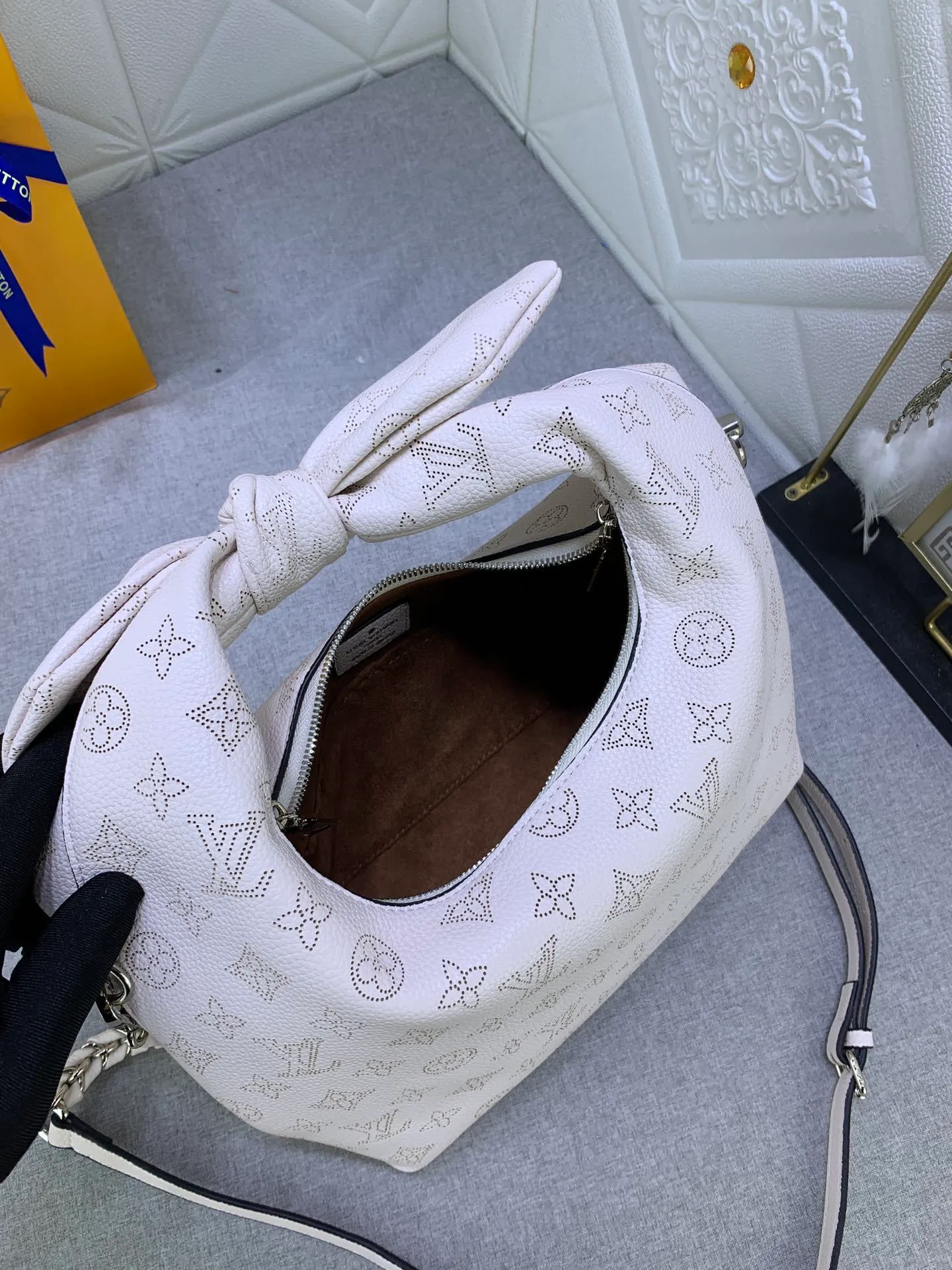 All categories Official website "Brand Women's Bags" Women's Bags 💙 LV Why Knot small handbag is made of Louis Vuitton's iconic Monogram engraved and perforated cow leather, combined with a knot-shaped handle, exuding a gentle style and modern atmosphere. Functional design holds everyday essentials such as a cell phone, wallet, keys, and sunglasses, and the removable woven leather chain allows for easy shoulder wear.