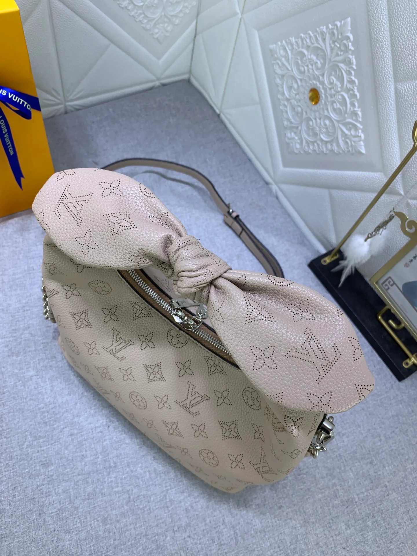 All categories Official website "Brand Women's Bags" Women's Bags 💙 LV Why Knot small handbag is made of Louis Vuitton's iconic Monogram engraved and perforated cow leather, combined with a knot-shaped handle, exuding a gentle style and modern atmosphere. Functional design holds everyday essentials such as a cell phone, wallet, keys, and sunglasses, and the removable woven leather chain allows for easy shoulder wear.