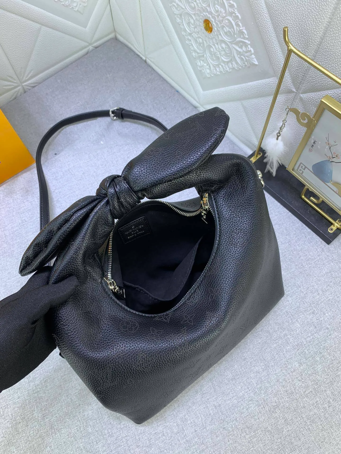 All categories Official website "Brand Women's Bags" Women's Bags 💙 LV Why Knot small handbag is made of Louis Vuitton's iconic Monogram engraved and perforated cow leather, combined with a knot-shaped handle, exuding a gentle style and modern atmosphere. Functional design holds everyday essentials such as a cell phone, wallet, keys, and sunglasses, and the removable woven leather chain allows for easy shoulder wear.