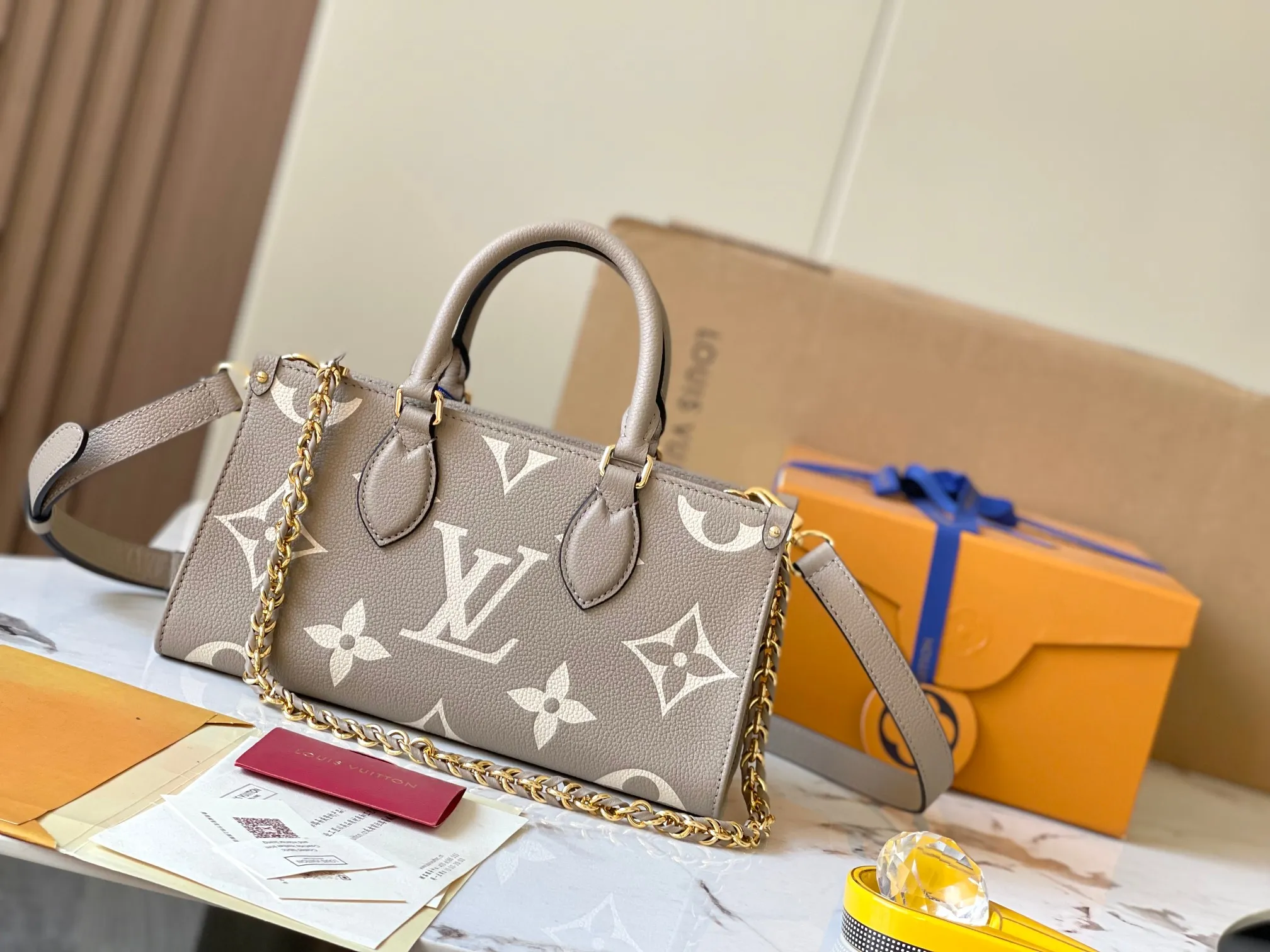 p1440 [Original leather, 💋 M23641 elephant gray] This OnTheGo small handbag is made of Monogram Empreinte leather with a Giant Monogram pattern embossed on it, highlighting its soft and slender silhouette. The compact interior keeps your daily essentials organized, while the articulated top handle and detachable leather and woven chain shoulder strap allow for a variety of carrying options. 25 x 13 x 10 cm (length x height x width)