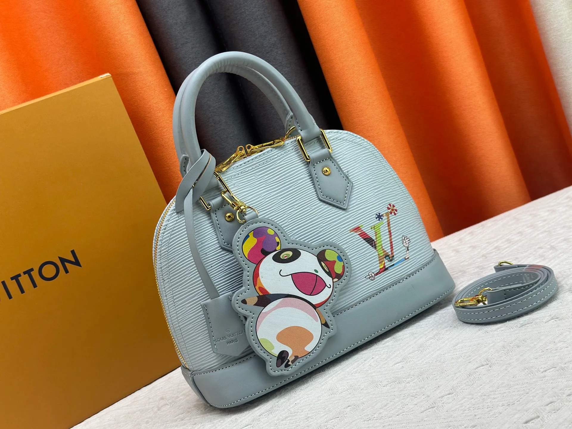p300 Upgraded original M13670 M14197 M53152 This Alma BB handbag is made of Epi leather and appears in the Louis Vuitton x Murakami reissue series. The smart LV letters on the front reflect the Japanese artist's "ultra-flat" aesthetic, which contrasts with the removable distinctive panda decoration. Top handles, a removable shoulder strap and a dazzling padlock complete the Art Deco design. Dimensions: 23.5 x 17.5 x 11.5 cm (length x height x width)