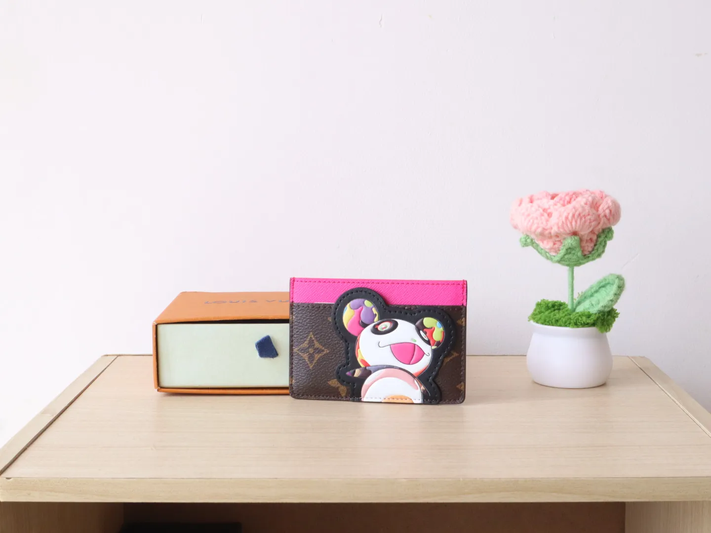 M13439 Card Holder🌟P280 LV x TM Business Card Holder This essential business card holder is reinterpreted with lively details from the Louis Vuitton x Murakami collaboration series, full of joy. The brand's classic Monogram pattern is covered with a bright panda pattern created by Japanese artists, which complements each other with a bright touch of pink on the top. Crafted from coated canvas, the business card holder has a stylish cut and multiple compartments to keep everyday essentials such as business cards and receipts organized.  11 x 7 x 0.5 cm