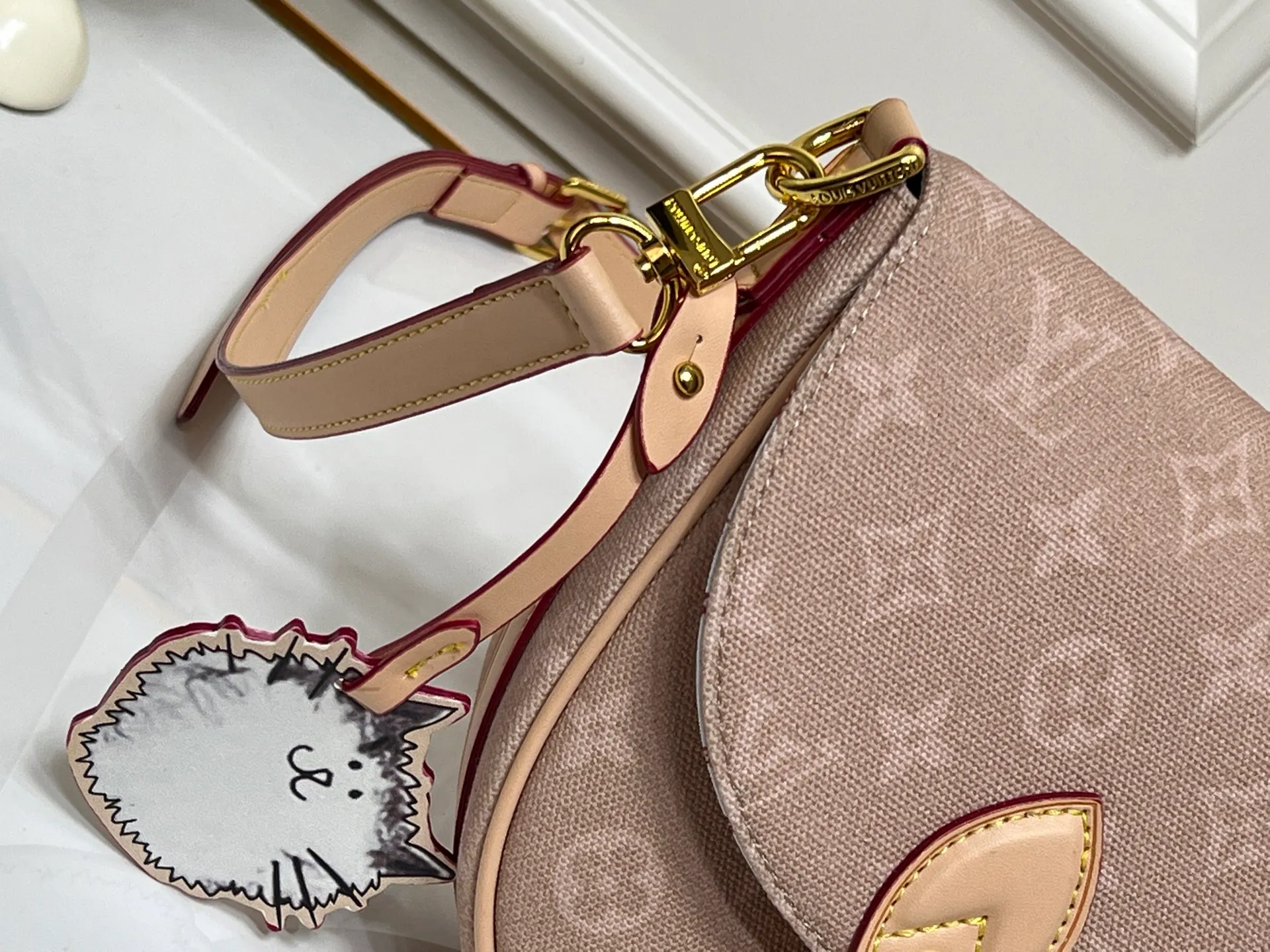 Batch 300💰 The M15134 Escape handbag makes its eye-catching appearance in the LV Travels With Grace Coddington series. It is a canvas bag with a fun Meowgram pattern and cat-shaped leather decoration hand-painted by Coddington himself. The flexible design provides a variety of carrying methods and can easily accommodate various daily needs. Dimensions: 21 x 7 x 30 cm