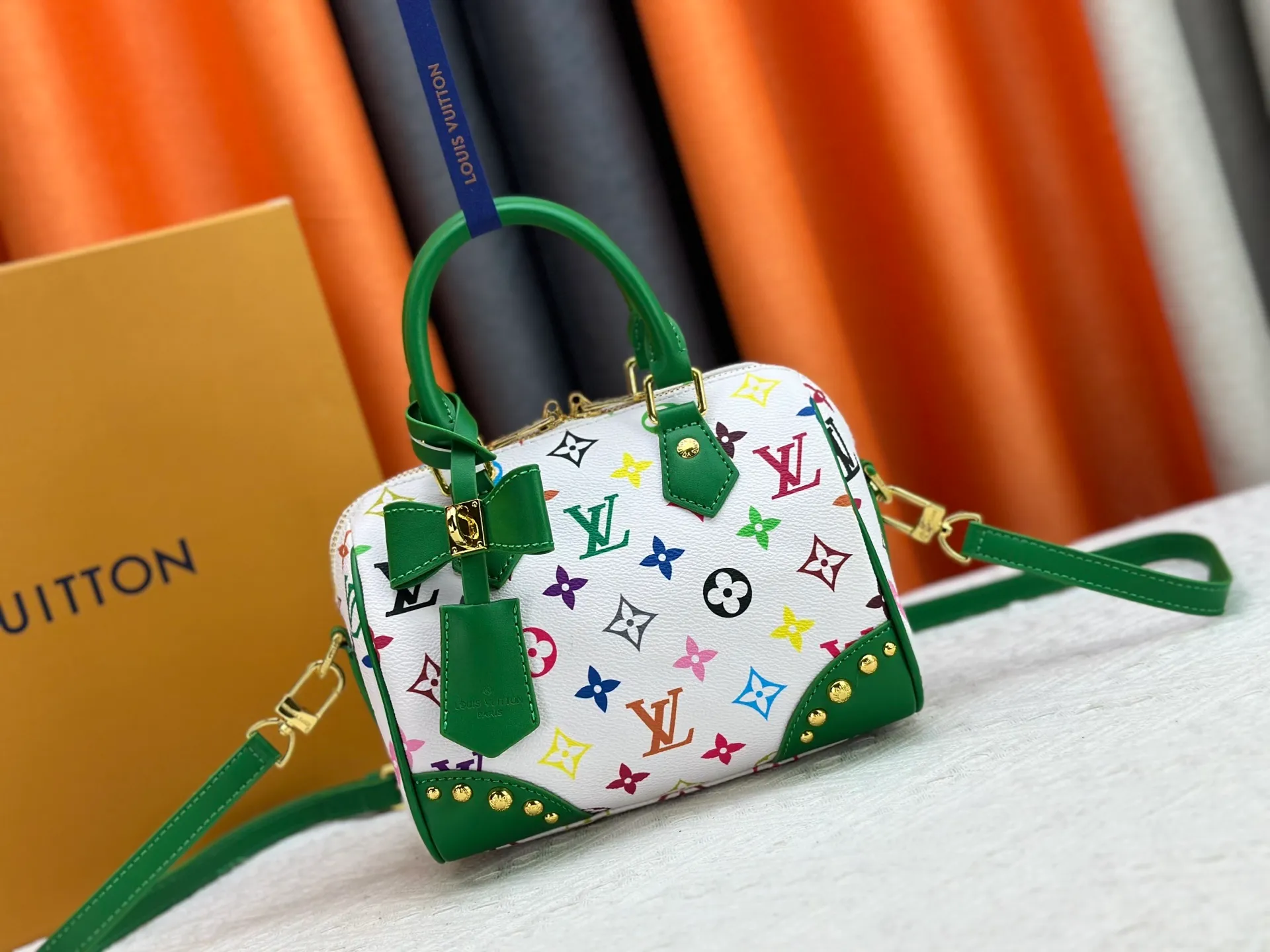P260 upgraded original M58953 M46234 M46222 Speedy Bandoulière 20 handbag is made of soft coated canvas, and the full-length Monogram pattern is traced in colorful rainbow tones, highlighting the smart style of the Louis Vuitton x Murakami reissue series. The Toron handle and detachable shoulder strap are constructed of cow leather, the metal corners recall classic luggage elements, and the bow-shaped key bag and padlock add brand touches. Dimensions: 20.5 x 13.5 x 12.0 cm (length x height x width)