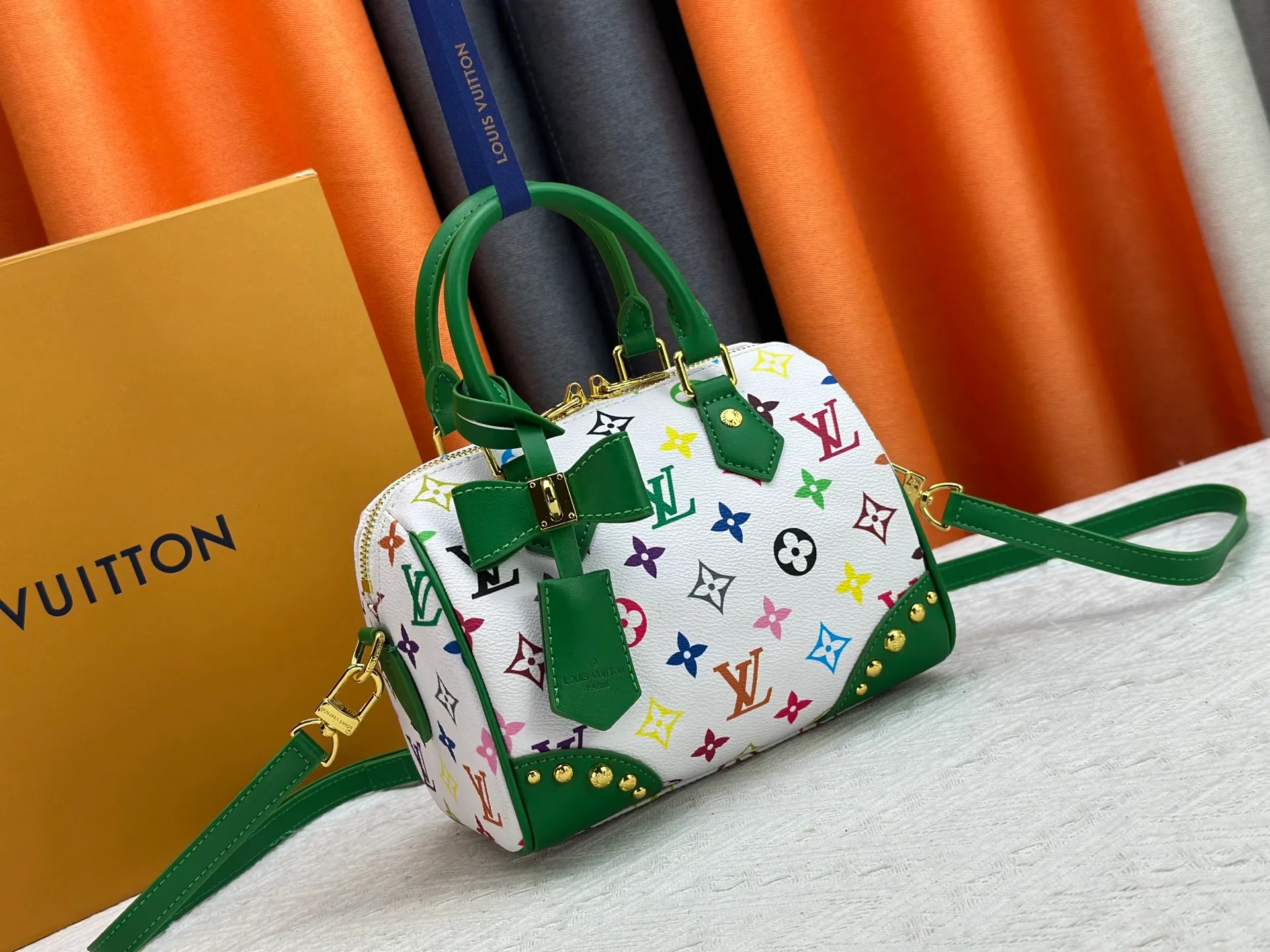 P260 upgraded original M58953 M46234 M46222 Speedy Bandoulière 20 handbag is made of soft coated canvas, and the full-length Monogram pattern is traced in colorful rainbow tones, highlighting the smart style of the Louis Vuitton x Murakami reissue series. The Toron handle and detachable shoulder strap are constructed of cow leather, the metal corners recall classic luggage elements, and the bow-shaped key bag and padlock add brand touches. Dimensions: 20.5 x 13.5 x 12.0 cm (length x height x width)
